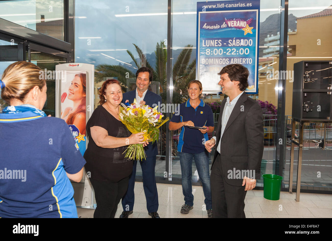 Der erste Kunde in einem neu eröffneten Lidl-Supermarkt präsentiert sich mit einem Strauß Blumen vom Manager, Puerto Santiago, Teneriffa, Kanarische Inseln, Spanien. Stockfoto