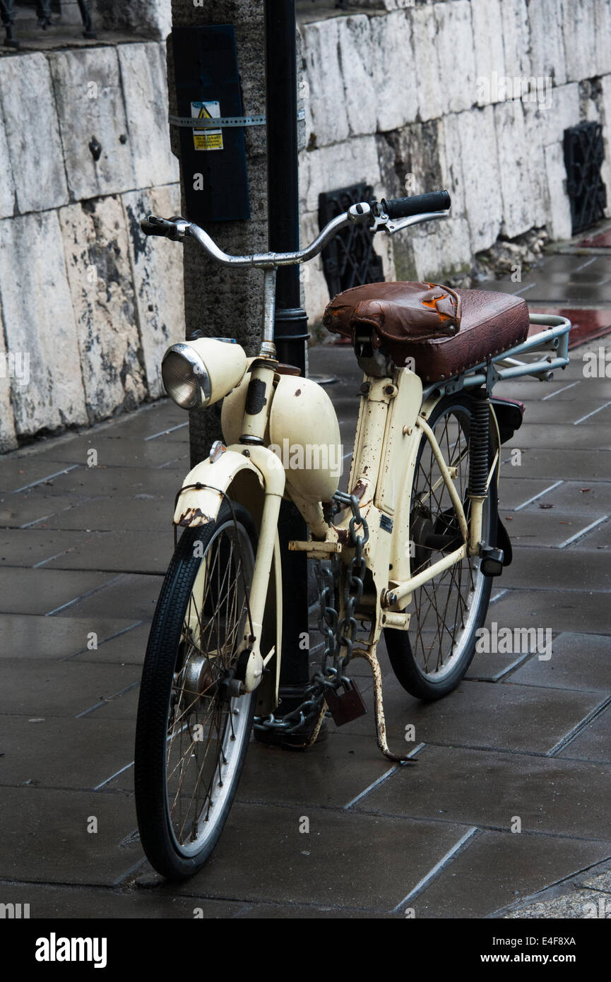 Ein altes Moped, angekettet an einen Pfosten auf einer Straße in Krakau. Stockfoto