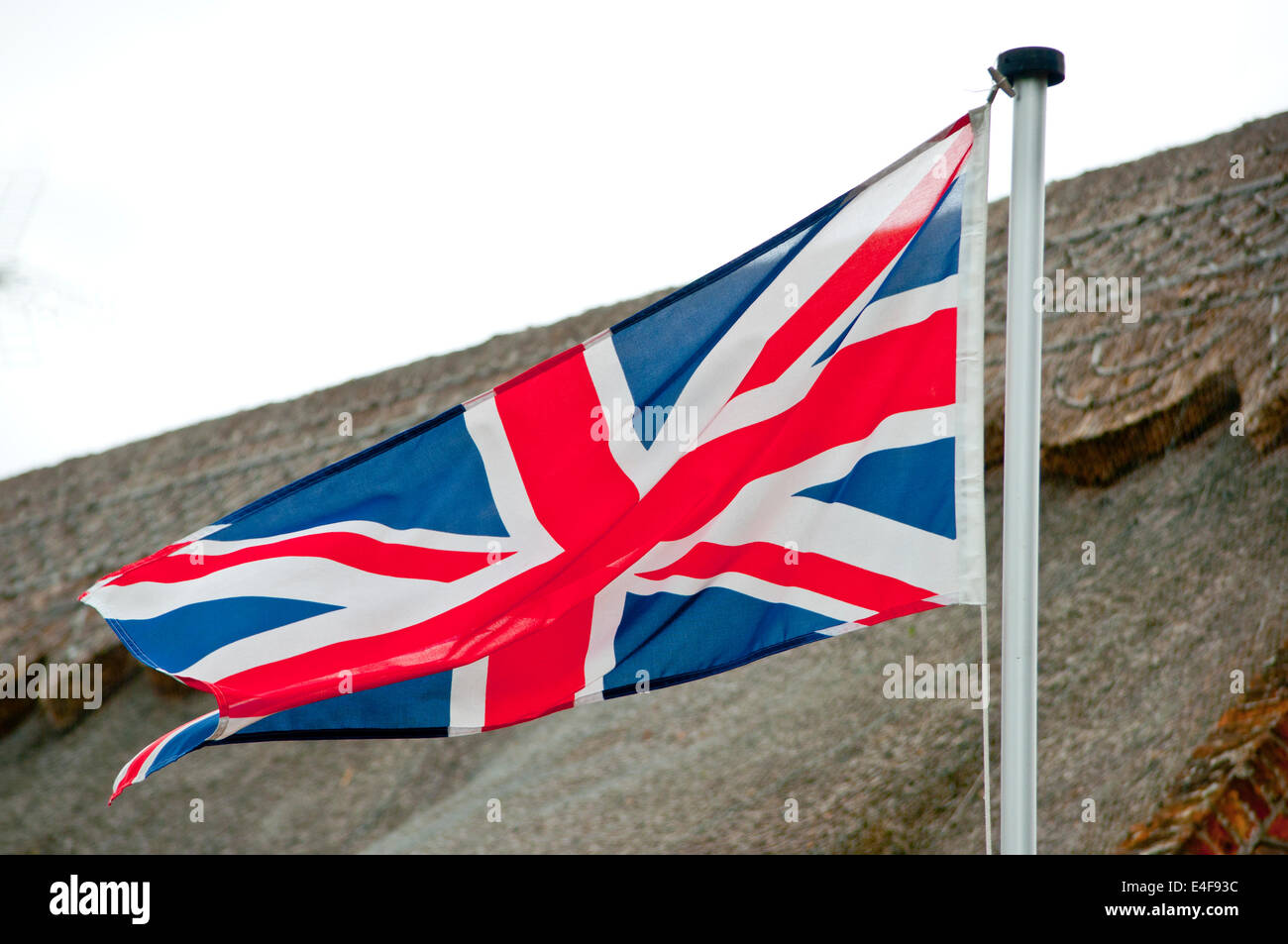Britischen Union Jack-Flagge mit Reetdach Ferienhaus im Dorf Stockfoto