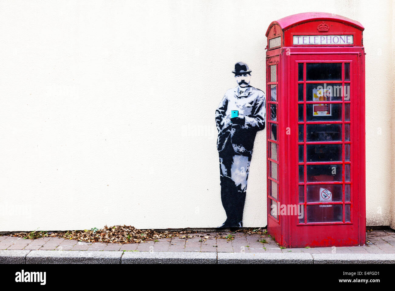 Banksy Stil Wandbild Graffiti rote Telefonzelle in Great Malvern Worcestershire UK England Stockfoto