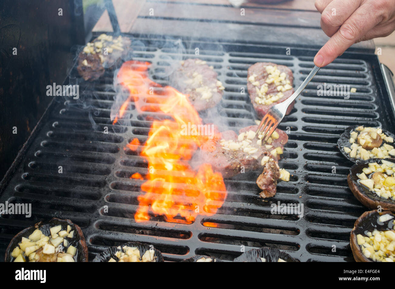 Man grillen Steaks und Champignons mit Knoblauch mit einem gasbefeuerten  Grill Stockfotografie - Alamy