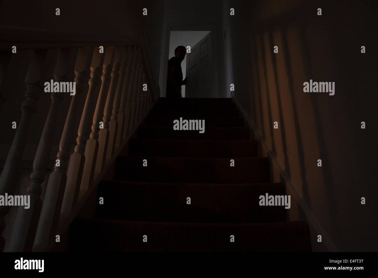 Silhouette eines Mannes Blick aus einem Zimmer am oberen Rand der Treppe, die Tür ist leicht geöffnet. Finden Sie ähnliche Bilder. Stockfoto