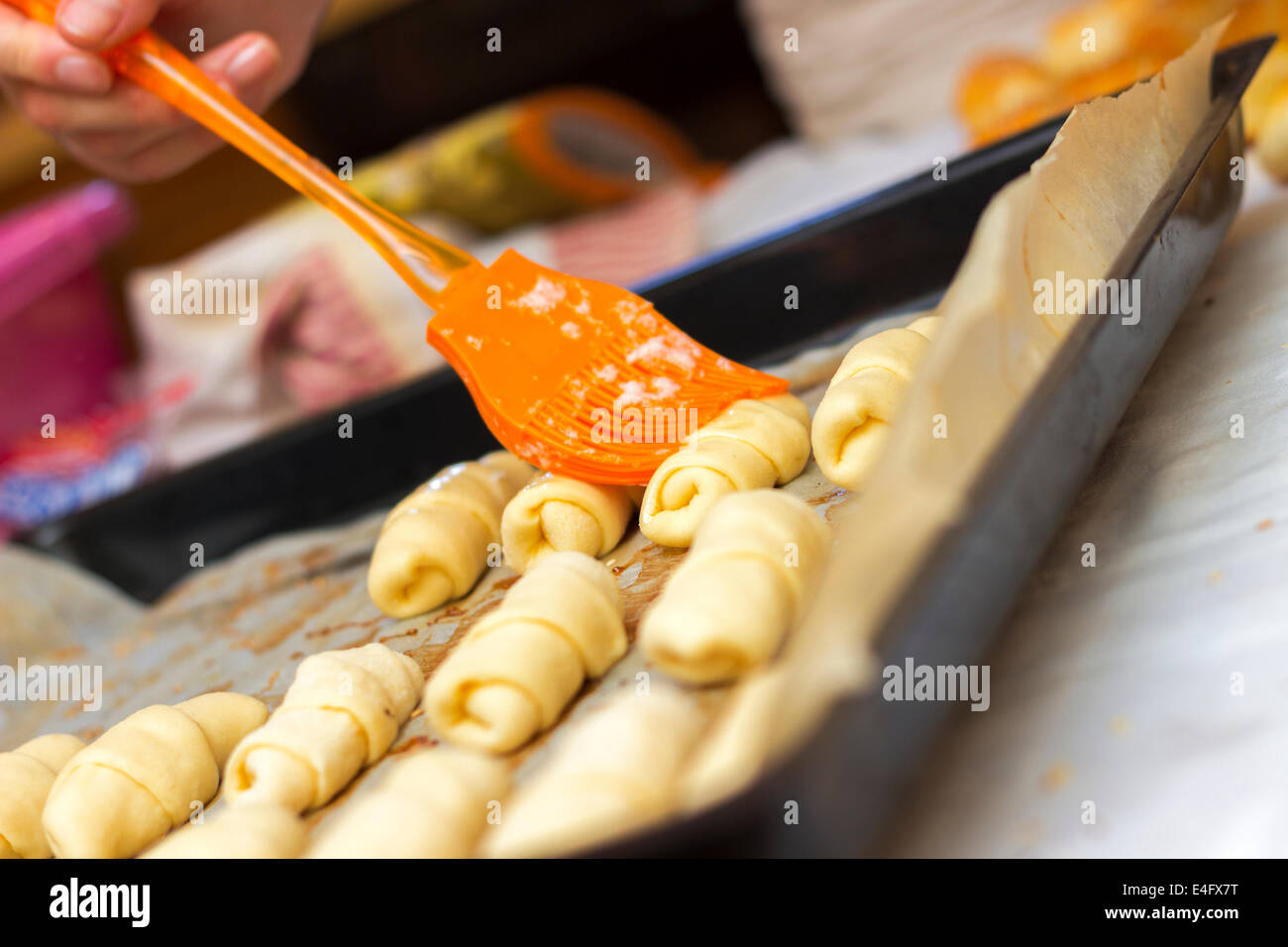 Baker setzen verquirltem Ei Mantel oben auf frisch Mini-Croissants nur vor dem Backen sie aufgerollt Stockfoto