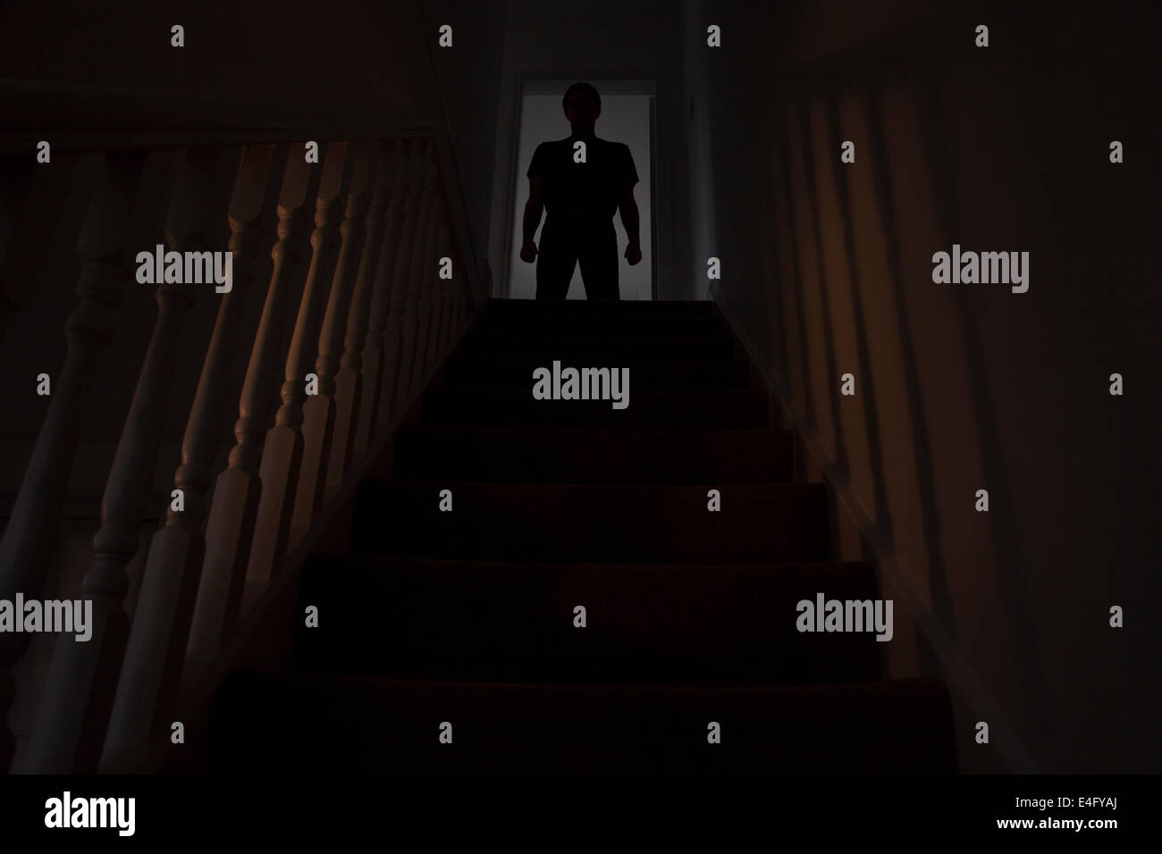 Silhouette eines Mannes stehen an der Spitze einer Treppe, Schatten an den Wänden des Lichts unter. Stockfoto