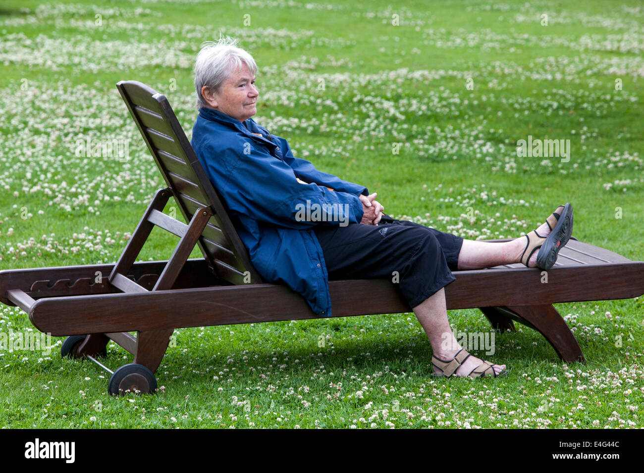 Ältere Frau auf einer Holzbank, eine alte Frau auf einer Bank Stockfoto