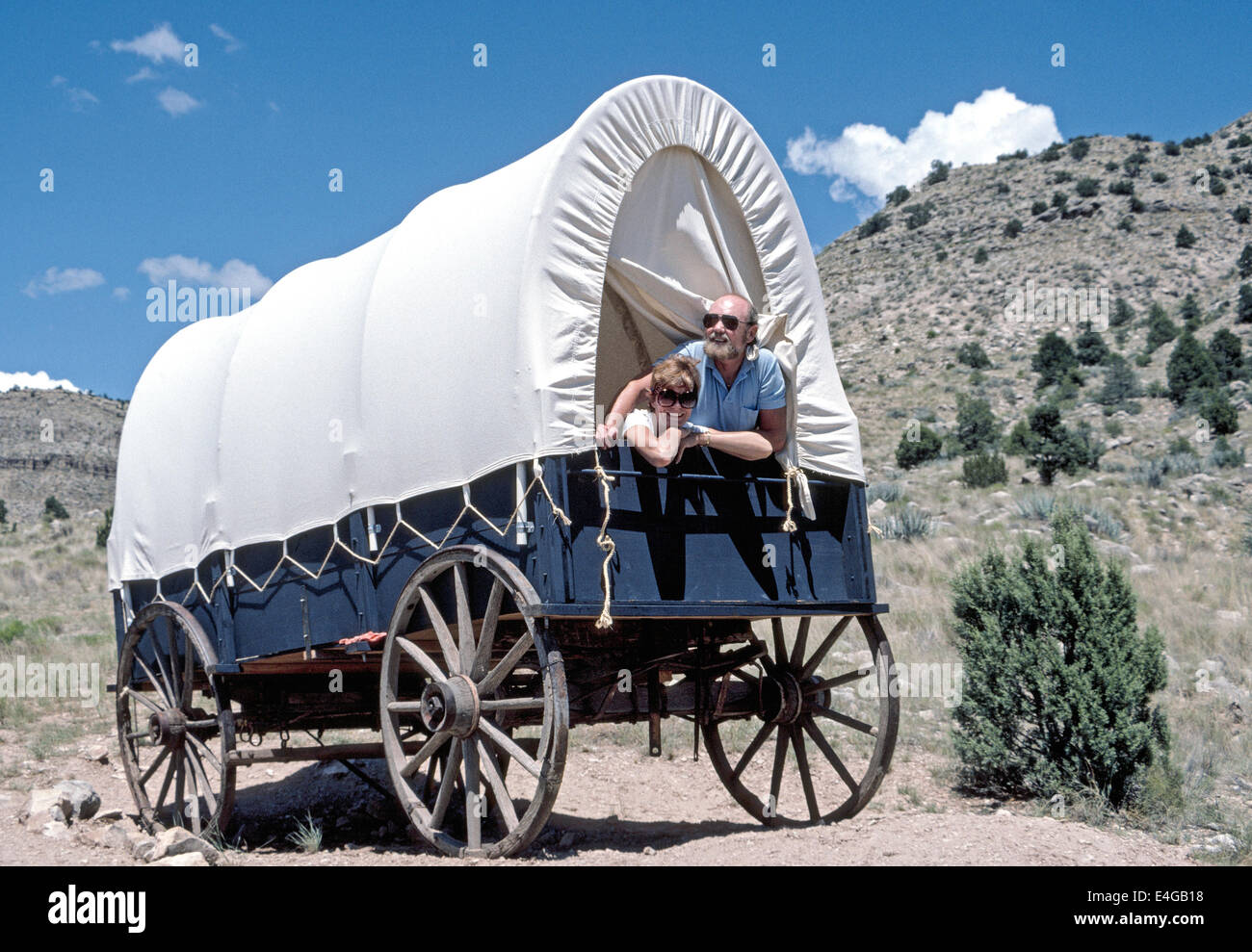 Eine abenteuerlustige Paar sieht von einem Planwagen, die ihre ungewöhnliche Schlafzimmer Unterkunft auf Bar 10 Ranch hoch über dem Grand Canyon in Arizona, USA. Stockfoto