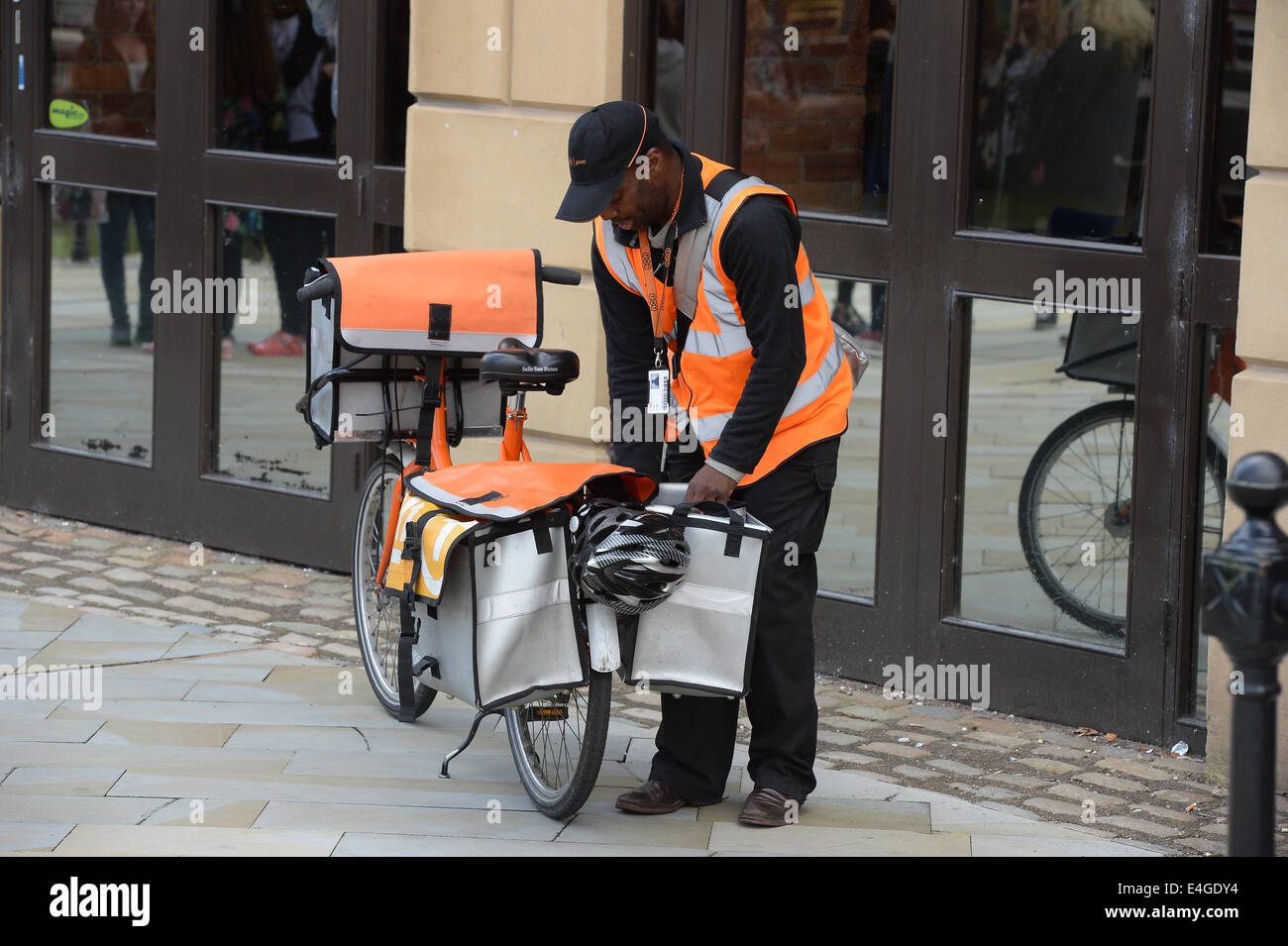 Ein TNT Postbote liefert Post an eine Adresse in Manchester City Centre, Stockfoto