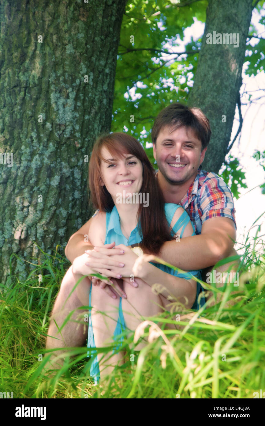 Lächelnde paar ruht in der Nähe eines Baumes Stockfoto