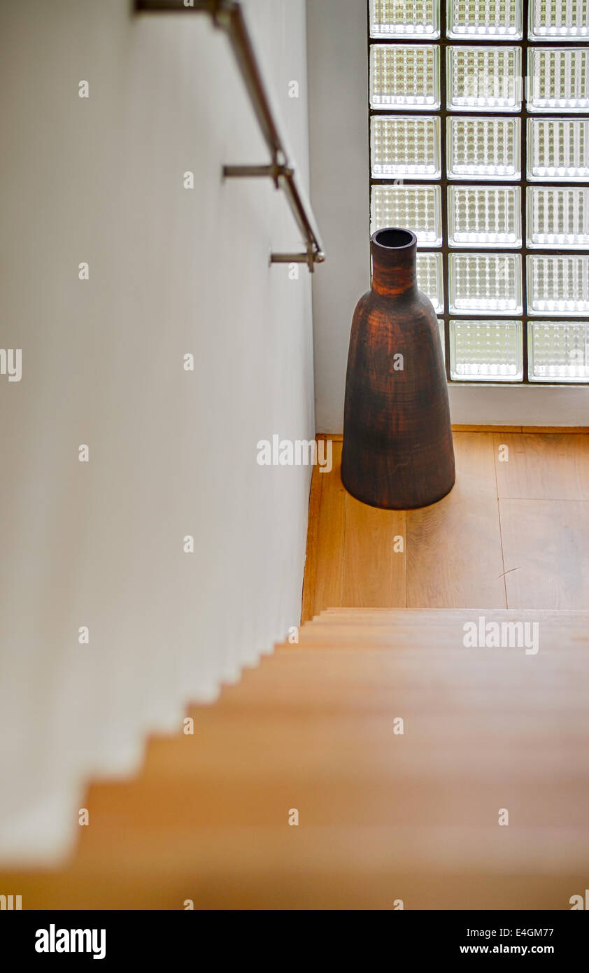 Flur mit Treppe hinunter und große Vase am Fenster, vertikale Position, nach unten. Stockfoto