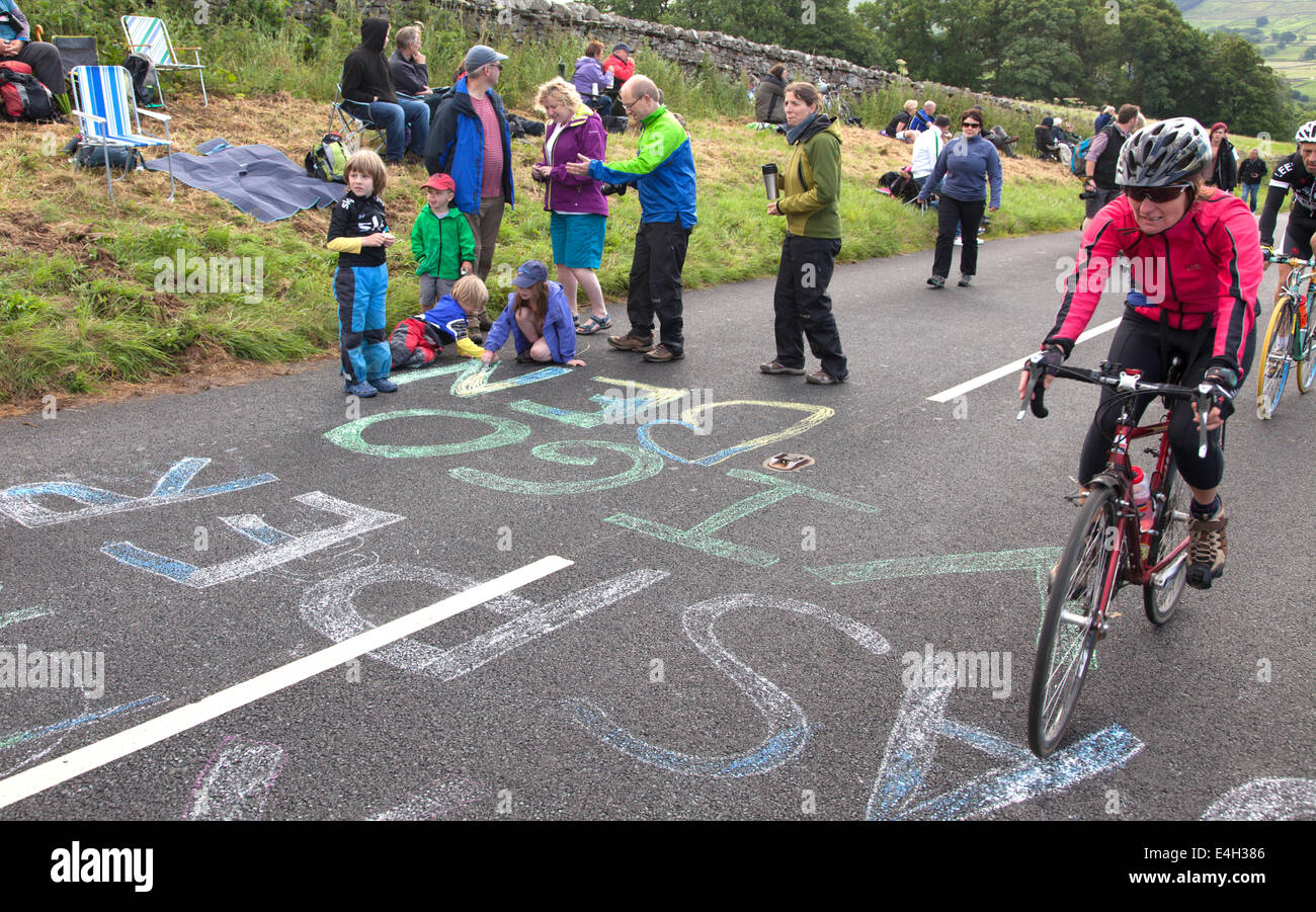 Kinder Kreidung Fahrer Namen auf der Straße vor der Ankunft der Tour De France in der Nähe von Hawes, North Yorkshire, England, UK Stockfoto