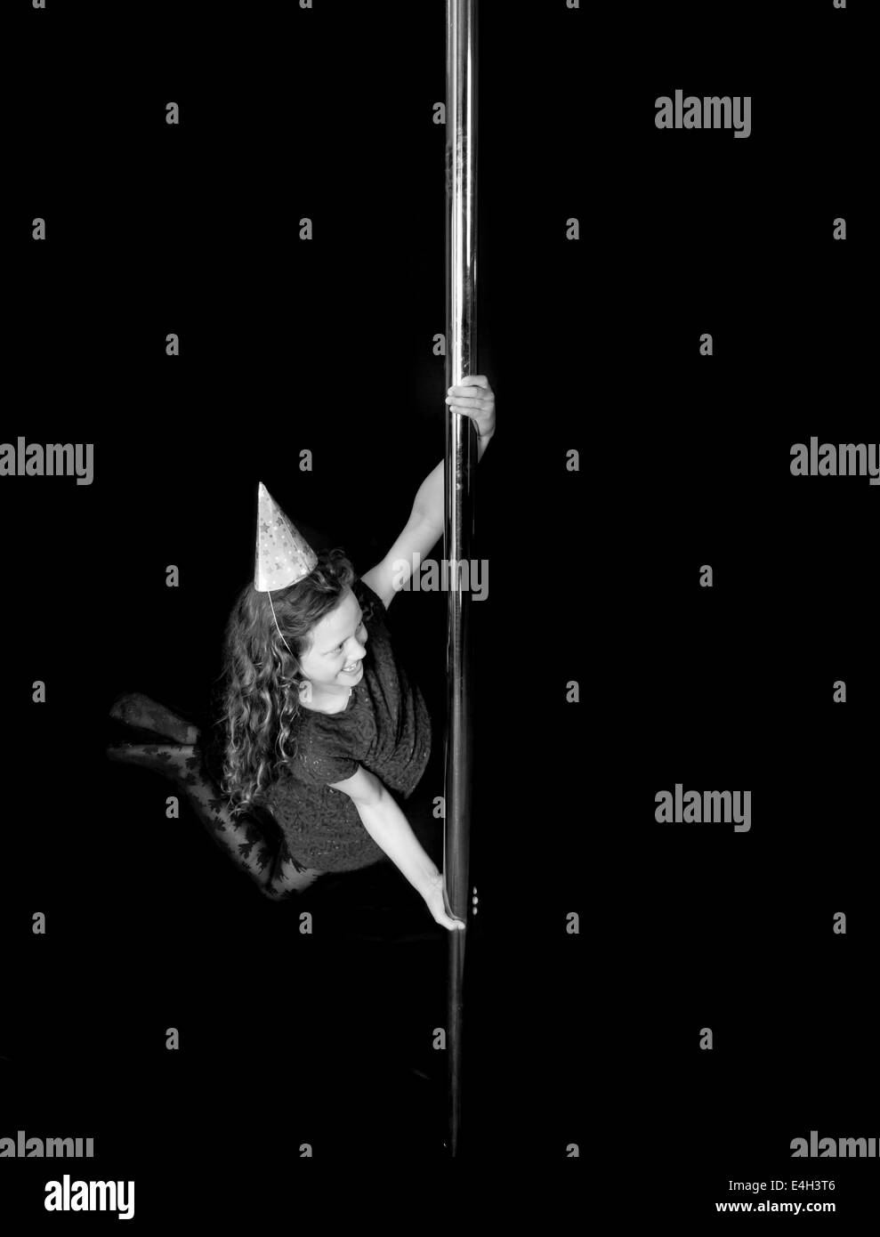 Ein junges Mädchen, das ihren Geburtstag feiert, spielt auf der Stange bei einer Pole-Fitness-Klasse. Stockfoto