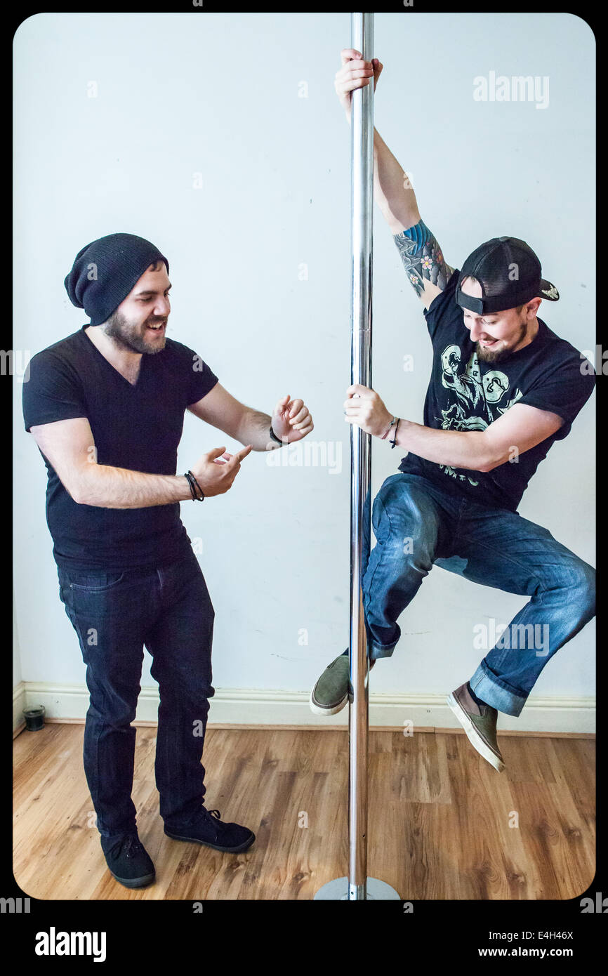 Zwei junge Männer, die auf einem Sportstock spielen und lernen, wie man Pole Dance spielt Stockfoto