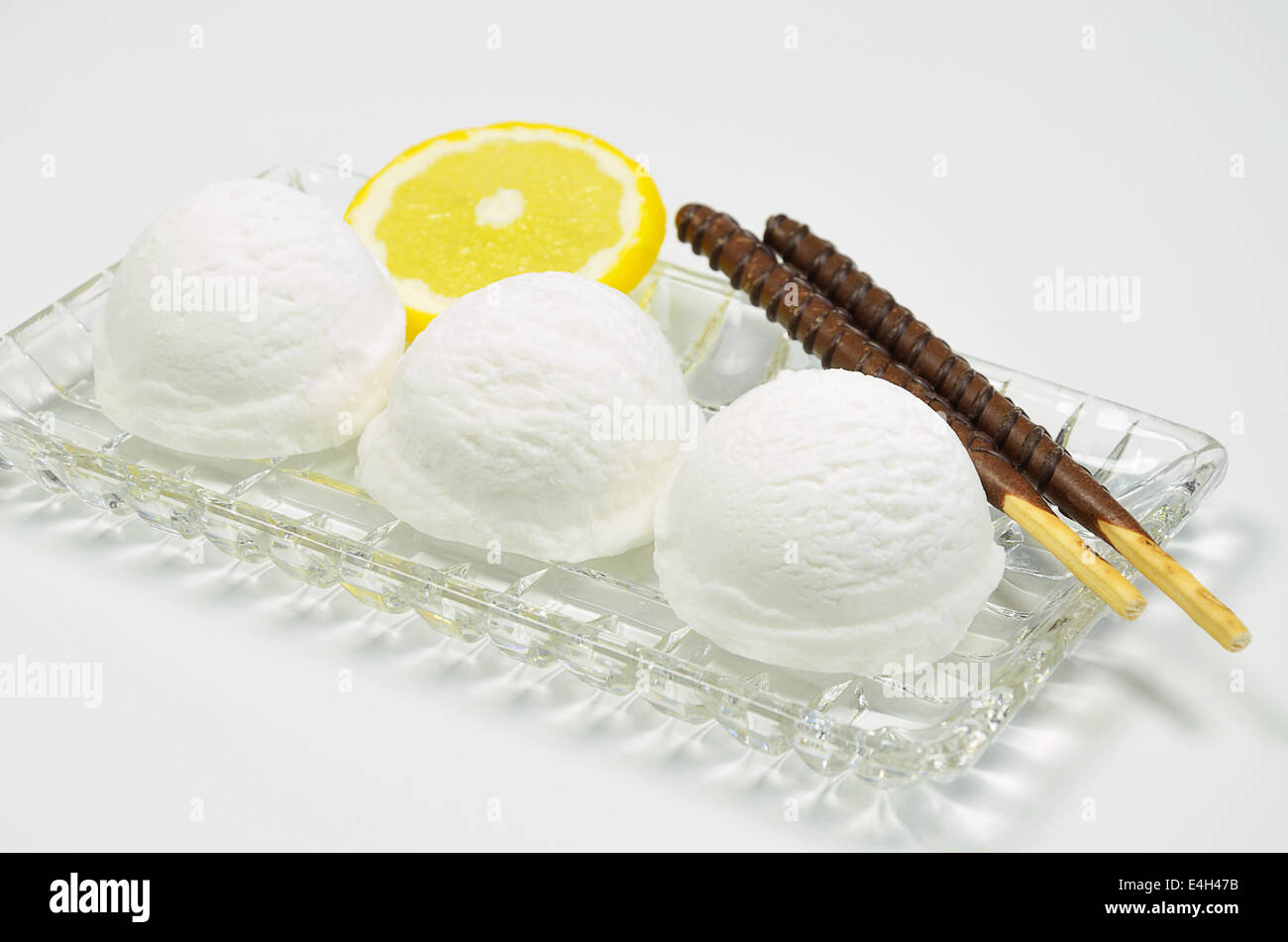drei Portionen Vanille Eis mit Schokolade Kekse und einer Scheibe Zitrone auf Glasplatte, Nahaufnahme, Stockfoto