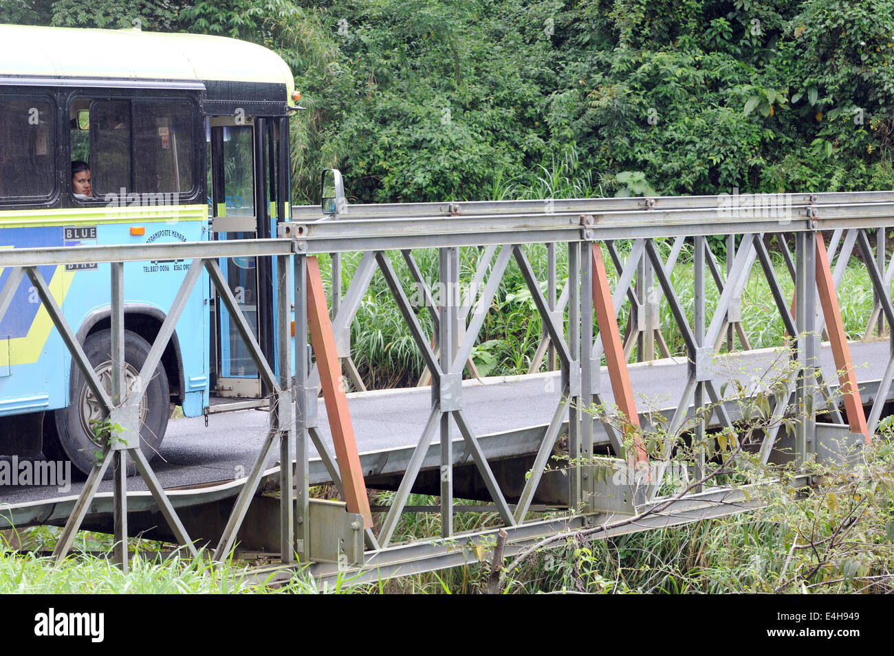 Ein Junge blickt aus dem Fenster eines blauen Busses, da es eine Brücke überquert. Santa Elena, Costa Rica... Stockfoto