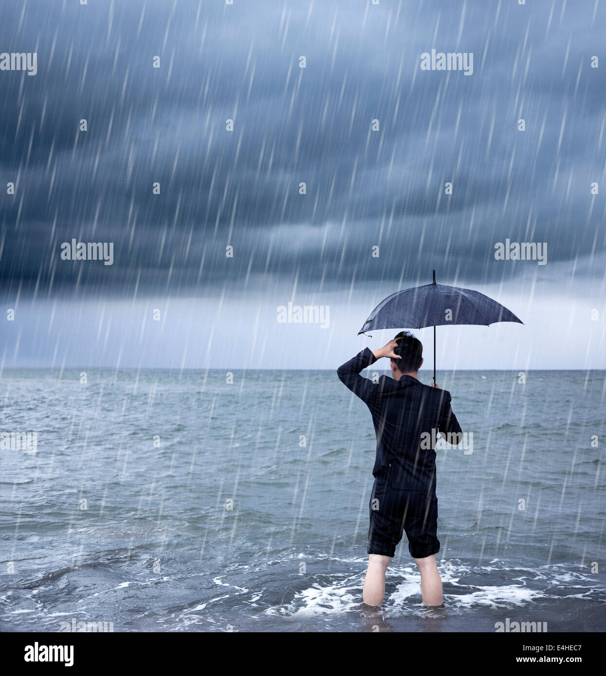 Business-Mann hält ein Dach mit Wolkenbruch Hintergrund verärgert Stockfoto