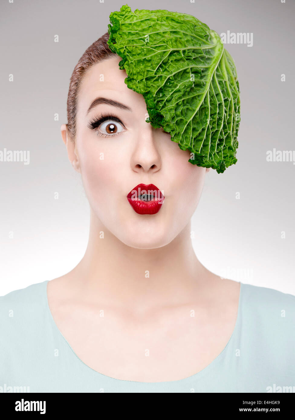 Porträt einer Frau, die zur Veranschaulichung einer Vegan-Konzepts mit einem Kohl auf dem Kopf Stockfoto
