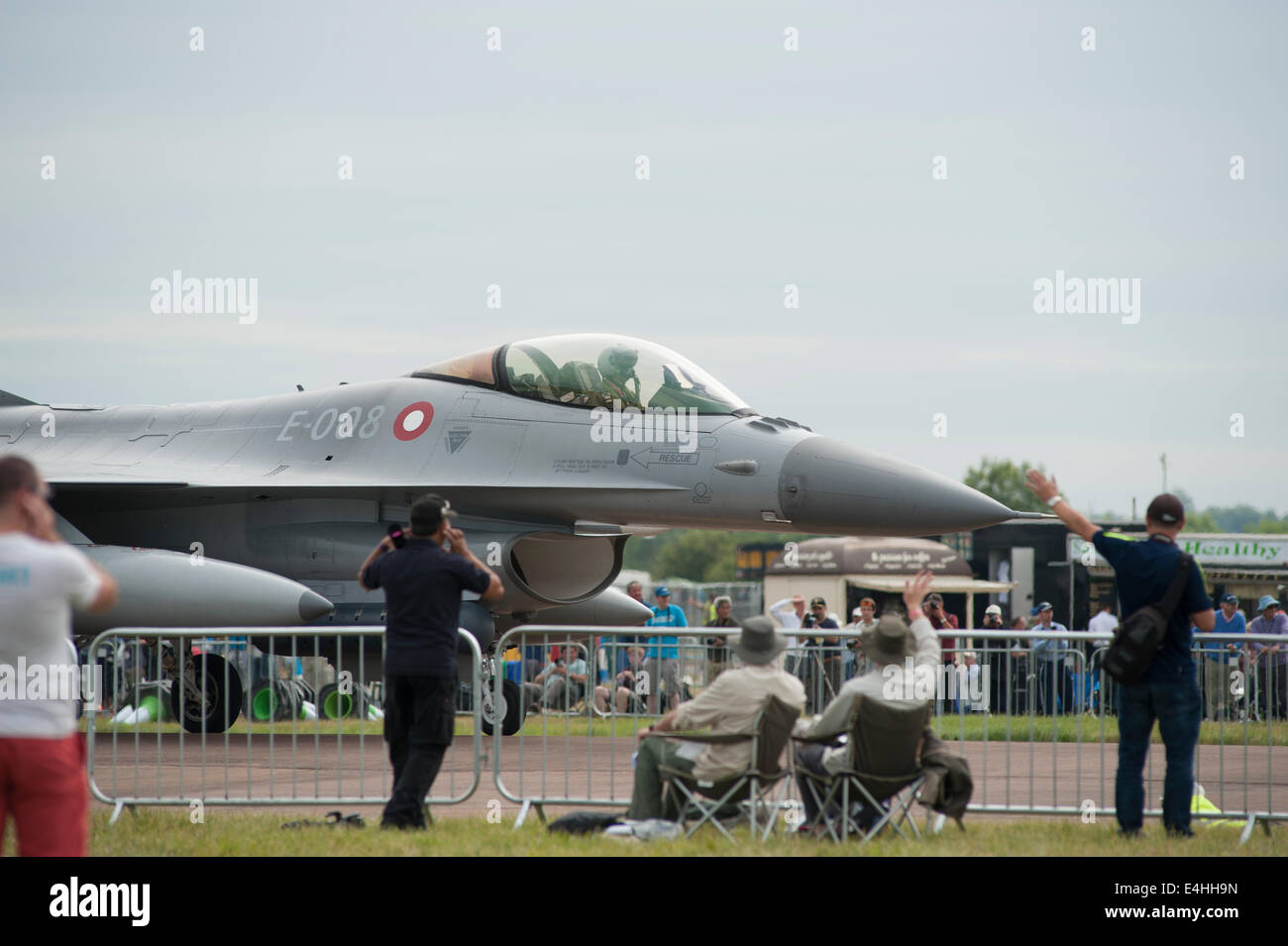 RAF Fairford, Gloucestershire UK. 11. Juli 2014. Zuschauer zu schützen, ihre Ohren und Welle, der Pilot von einem einzigen Sitz königliche dänische Luftwaffe Lockheed F-16 Falcon der Kämpfer Wing Skrydstrup RIAT angekommen. Bildnachweis: Malcolm Park Leitartikel/Alamy Live-Nachrichten Stockfoto