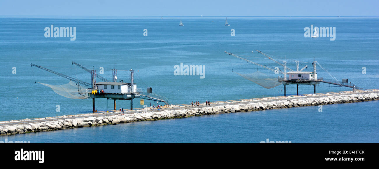 Ungewöhnliche Bild der öffentlichen Gehweg entlang Hafen Wellenbrecher & zwei Fishermens Hütten auf Stelzen gebaut, große Netze über dem Meer ausgesetzt Stockfoto