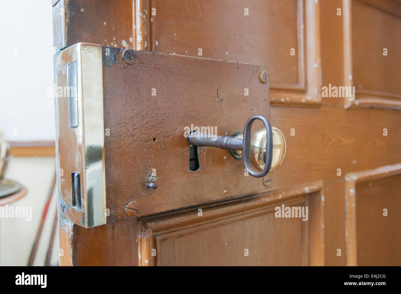 Schwere Messing Schloss auf der Innenseite der Tür, mit einem großen altmodischen Schlüssel. Stockfoto