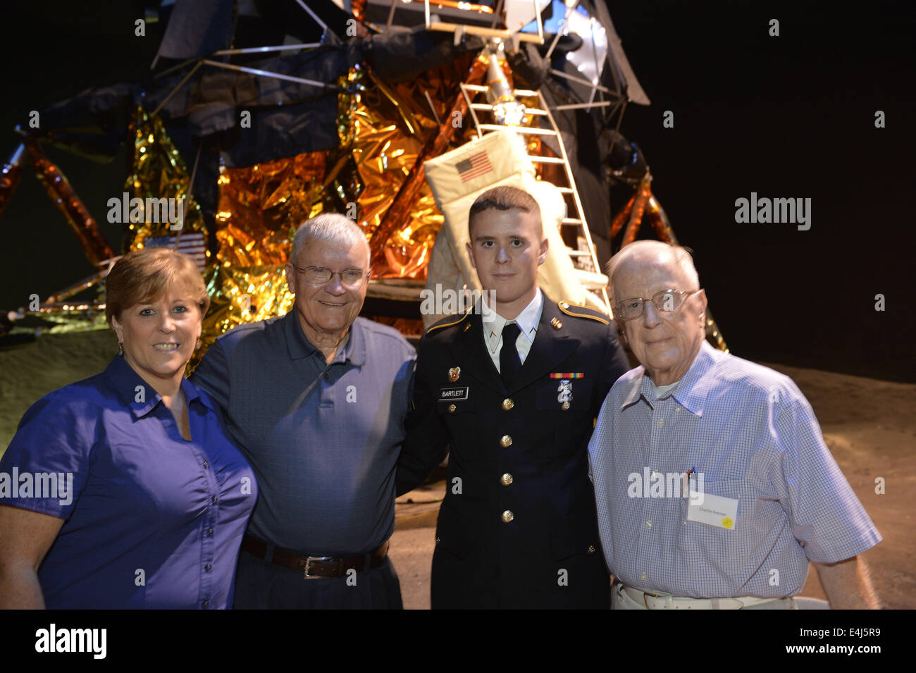 Garden City, New York, USA. 12. Juli 2014. L-R, CAROL BARTLETT, ehemaliger NASA Apollo Astronaut FRED HAISE, SEAN BARTLETT von East Stroudsbury, PA, US Army Reserve einheitliche, tragen und Großvater CHARLIE KEENAN, 85, der Centerport, stehen im Sommer 69 Feier im Long Island Cradle of Aviation Museum, auf der 45. Jahrestag der NASA Apollo 11 LEM, Mondfähre, statt Landung auf dem Mond Juli 20 , 1969. Keenan, der Großvater von Sean und Carols Vater ist, ist ein Grumman-Rentner, die war ein LEM Strom Subsystem Ingenieur, zog mit seiner Familie in die ehemalige Graumman Stockfoto