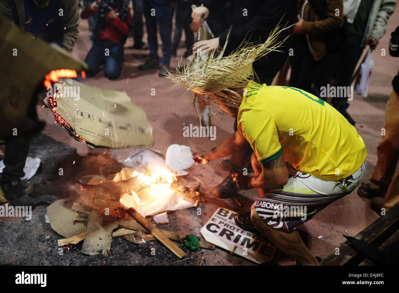 Sao Paulo, Brasilien. 12. Juli 2014. Ein Demonstrant trägt ein Hemd der brasilianischen Nationalmannschaft legt Feuer auf Bilder von Politik und Holzstücke während einer Protestaktion gegen die Inhaftierung von Aktivisten, die in einer früheren Demonstration gegen die Fifa WM 2014 in Roosevelt Platz verhaftet wurden. Bildnachweis: Tiago Mazza Chiaravalloti/Pacific Press/Alamy Live-Nachrichten Stockfoto