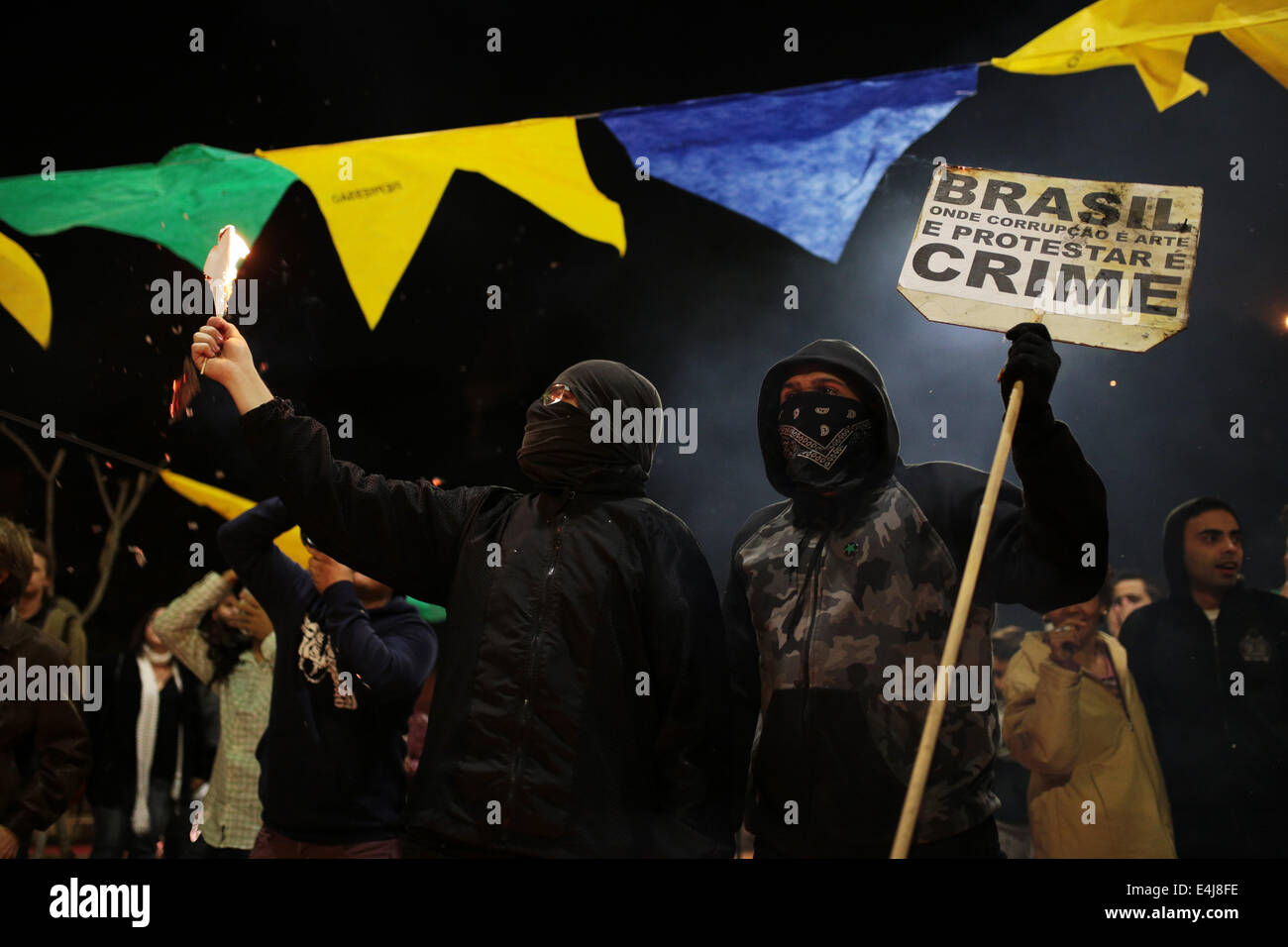 Sao Paulo, Brasilien. 12. Juli 2014. Ein maskierter Demonstrant hält ein Schild, das sagt "Brasilien, wo Korruption ist Kunst und Protest ist ein Verbrechen" bei einem Protest gegen die Inhaftierung von Aktivisten, die in einer früheren Demonstration gegen die FIFA WM 2014 in Roosevelt festgenommen wurden quadratische. Bildnachweis: Tiago Mazza Chiaravalloti/Pacific Press/Alamy Live-Nachrichten Stockfoto