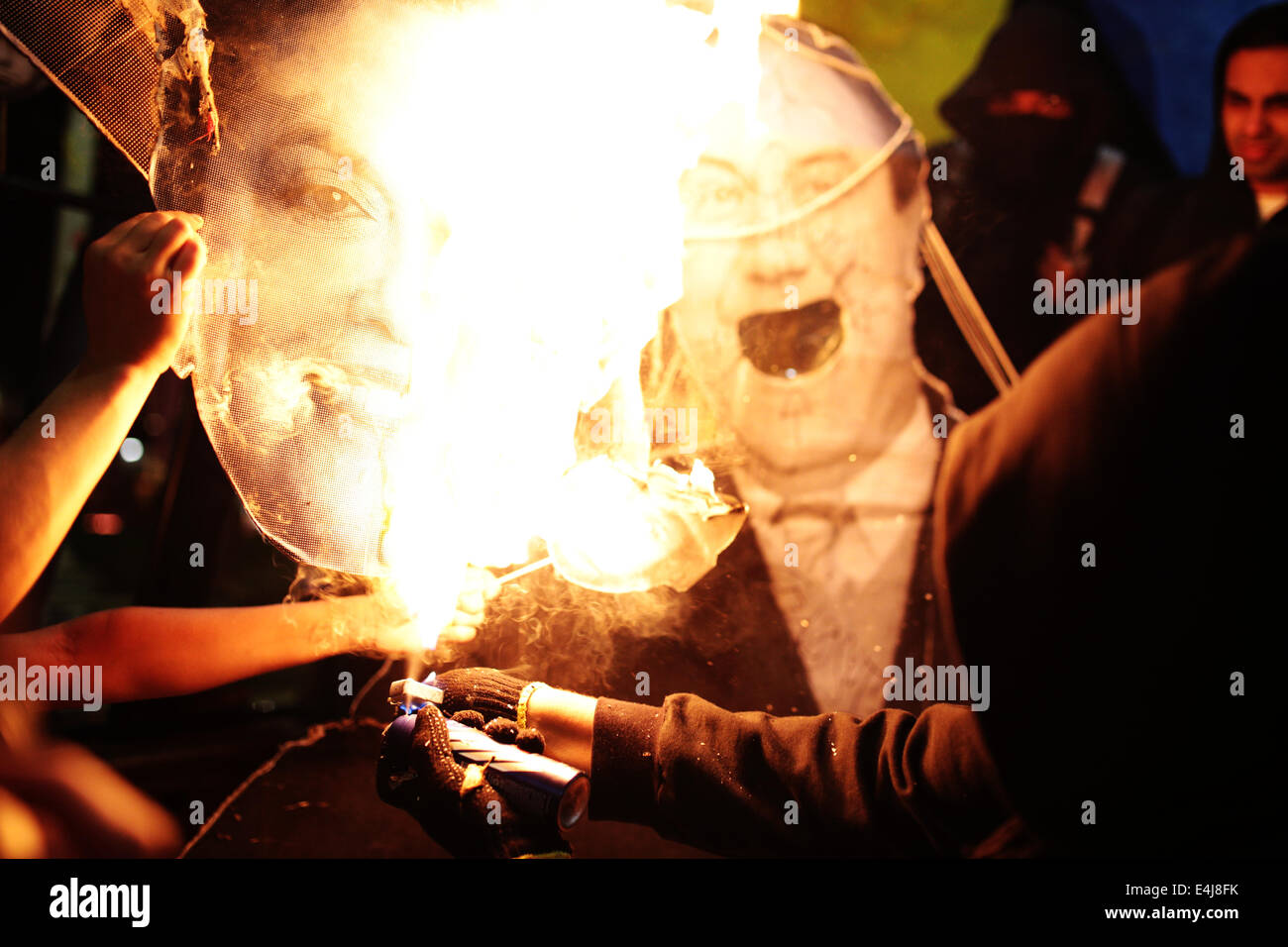 Sao Paulo, Brasilien. 12. Juli 2014. Ein maskierter Demonstrant verwendet ein Deodorant Spray, um ein Bild von der Präsidentin von Brasilien Dilma Rousseff während einer Protestaktion gegen die Inhaftierung von Aktivisten zu verbrennen, die in einer früheren Demonstration gegen die FIFA WM 2014 in Roosevelt-Platz festgenommen wurden. Bildnachweis: Tiago Mazza Chiaravalloti/Pacific Press/Alamy Live-Nachrichten Stockfoto