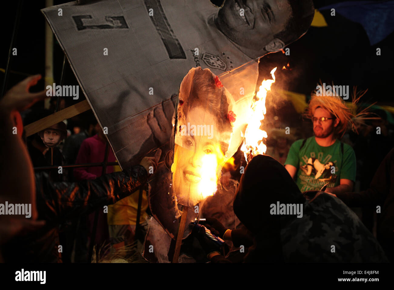 Sao Paulo, Brasilien. 12. Juli 2014. Ein maskierter Demonstrant verwendet ein Deodorant Spray, um ein Bild von der Präsidentin von Brasilien Dilma Rousseff und Ex-Spieler Ronaldinho bei einem Protest gegen die Inhaftierung von Aktivisten zu verbrennen, die in einer früheren Demonstration gegen die Fifa WM 2014 in Roosevelt-Platz festgenommen wurden. Bildnachweis: Tiago Mazza Chiaravalloti/Pacific Press/Alamy Live-Nachrichten Stockfoto