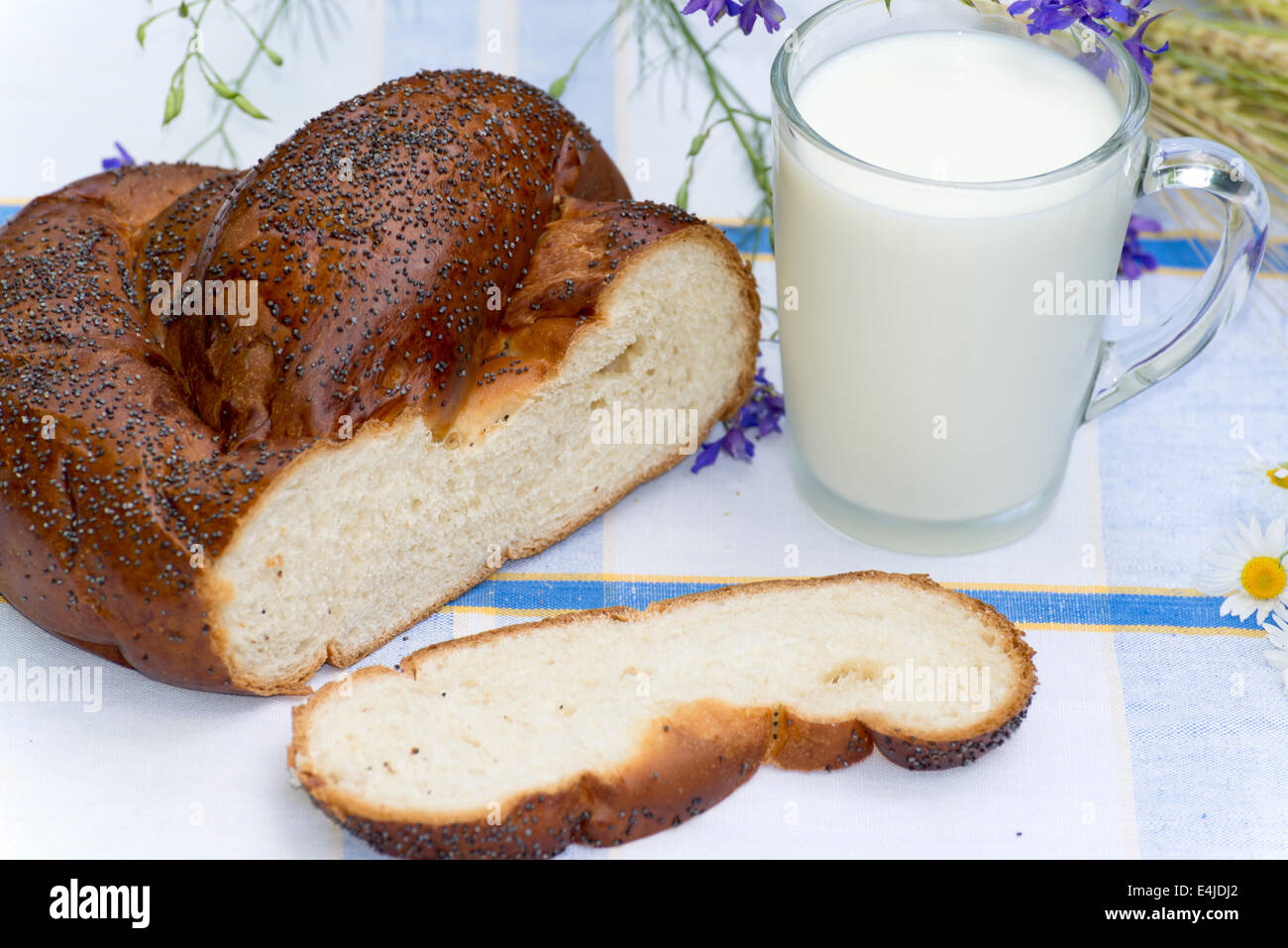Tasse Milch und Brötchen mit Mohn Stockfoto