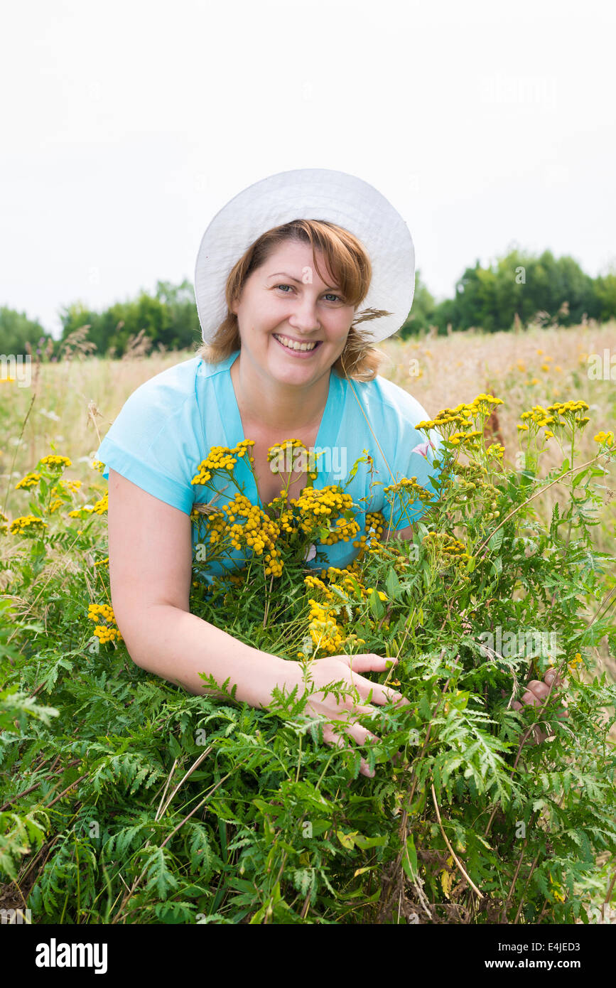 Frau mittleren Alters auf einer Wiese mit Rainfarn Stockfoto