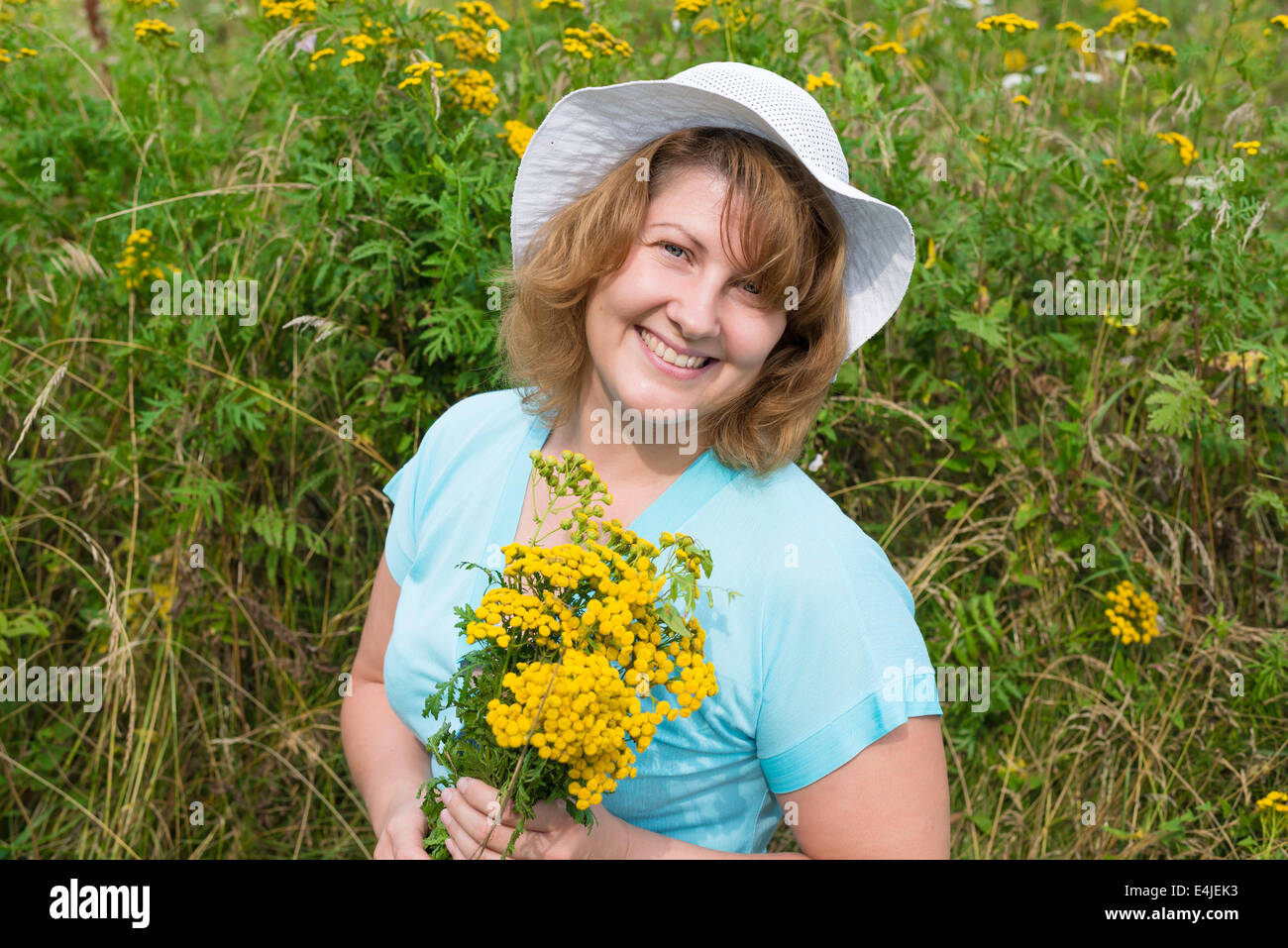 Frau mittleren Alters auf einer Wiese mit Rainfarn Stockfoto