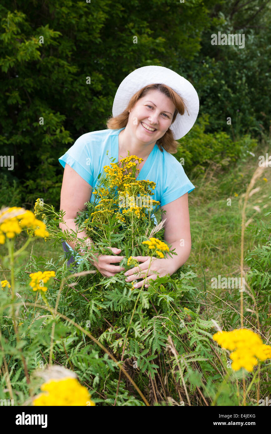 Frau mittleren Alters auf einer Wiese mit Rainfarn Stockfoto