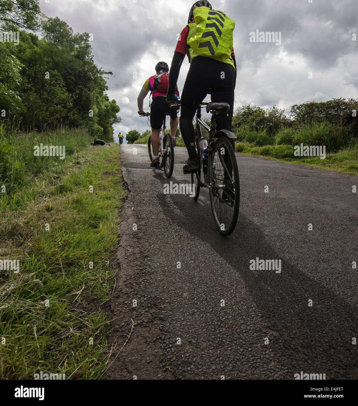 Radfahrer, Radfahren auf einem Hügel zwischen Haltwhistle und zweimal in Northumberland gebraut unter einem schweren Himmel. Stockfoto