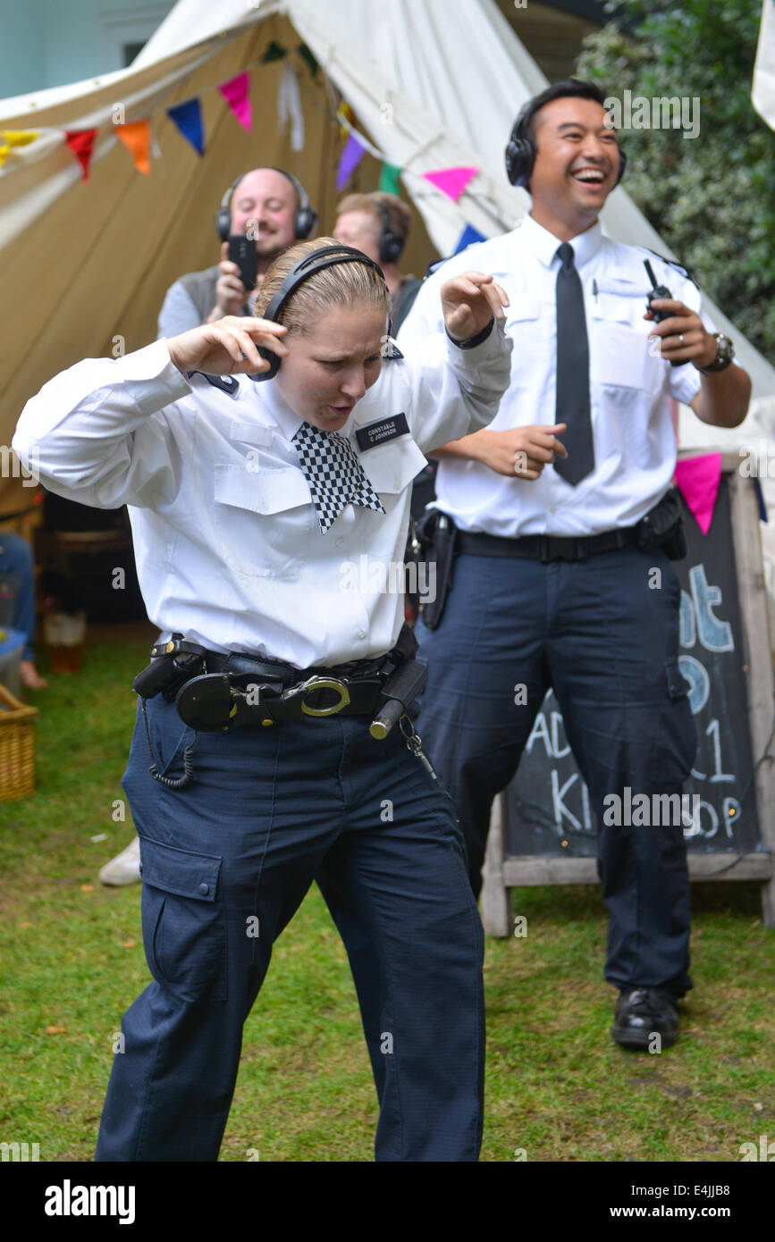 Soho, London, UK. 13. Juli 2014. Offiziere auf dem Schlag: Polizisten tanzen zu eine silent Disco, The Soho Village Fete feiert sein 40. Jahr mit Ständen, Unterhaltung und die Rückkehr des Rennens Kellner. Bildnachweis: Matthew Chattle/Alamy Live-Nachrichten Stockfoto