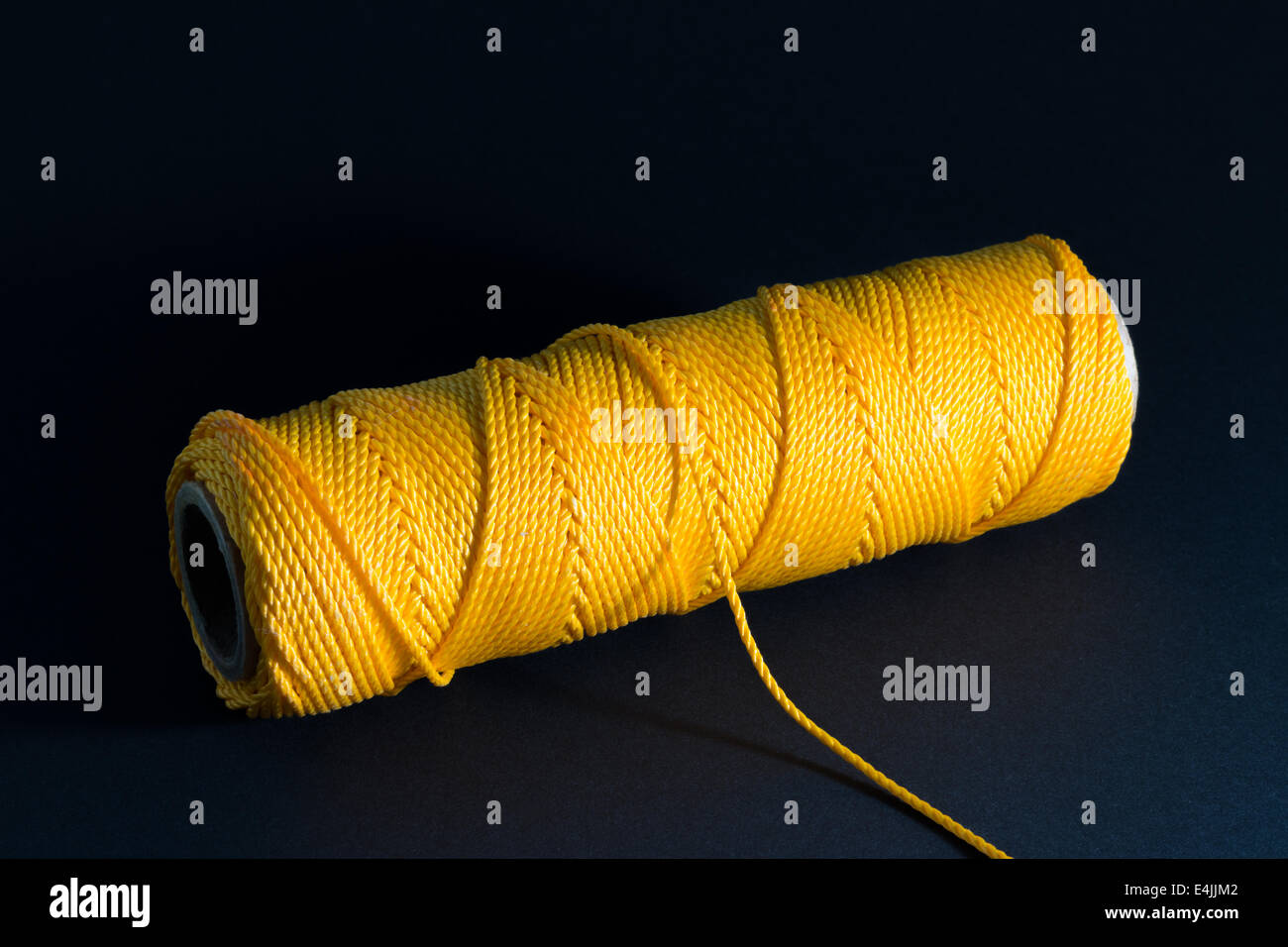 Fadenspule mit gelben Faden auf dunklem Hintergrund Stockfoto