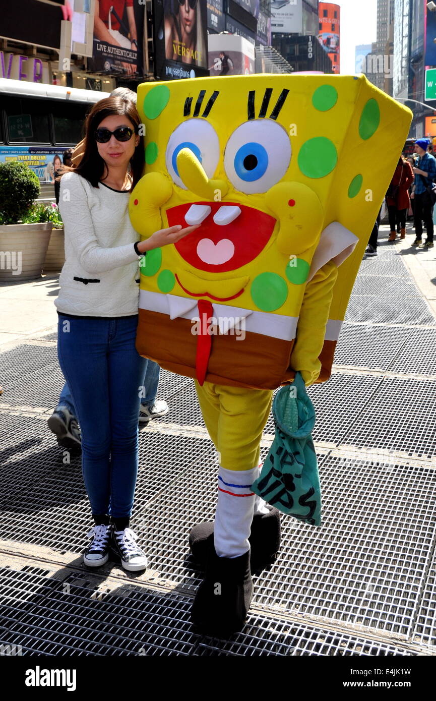 New York City: Junge Frau posiert für ein Foto mit Sponge Bob Charakter auf dem Times Square Stockfoto