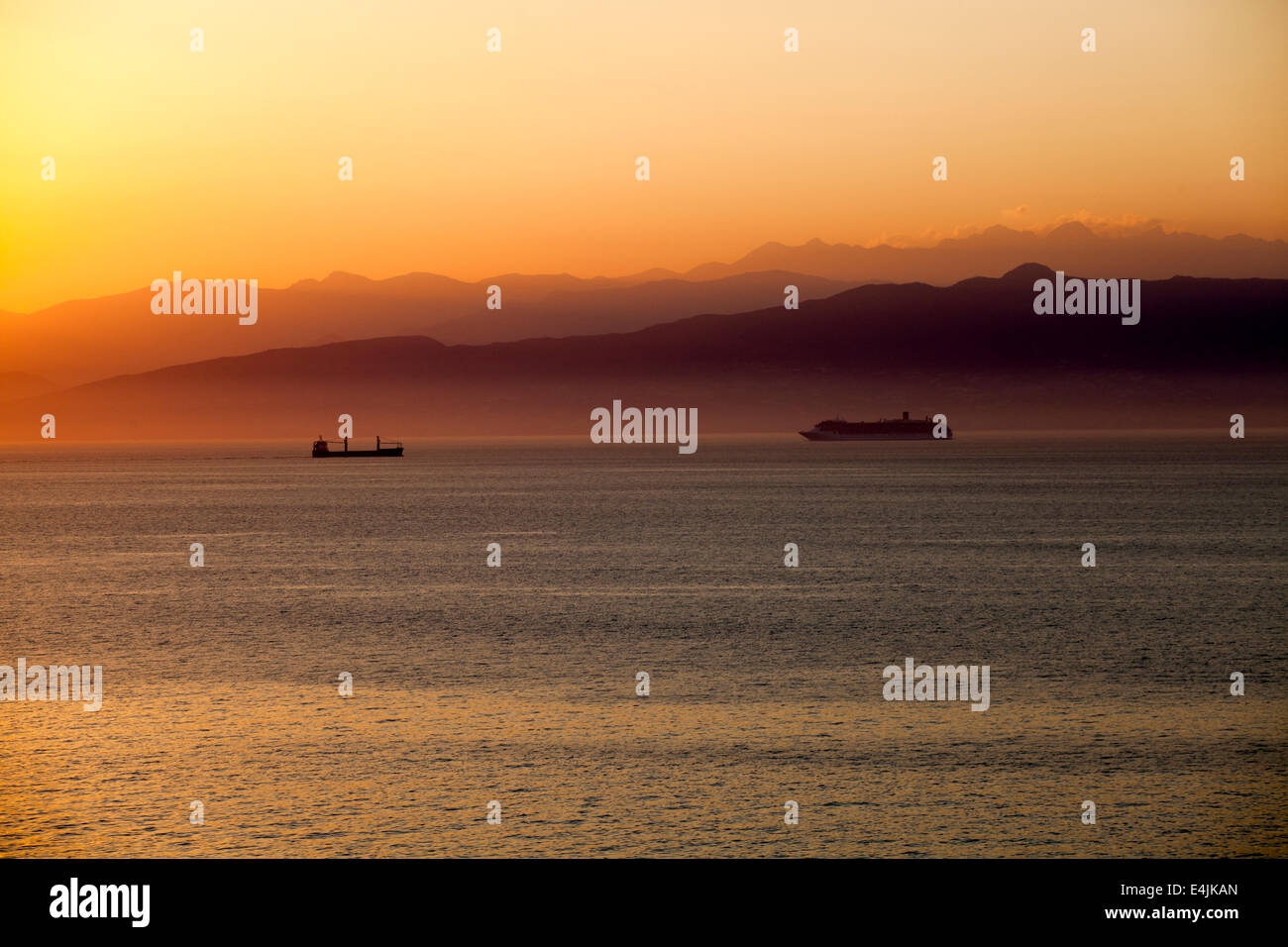 Einen wunderschönen mediterranen Sonnenuntergang mit einem Kreuzfahrtschiff mit Bergen im Hintergrund. Stockfoto