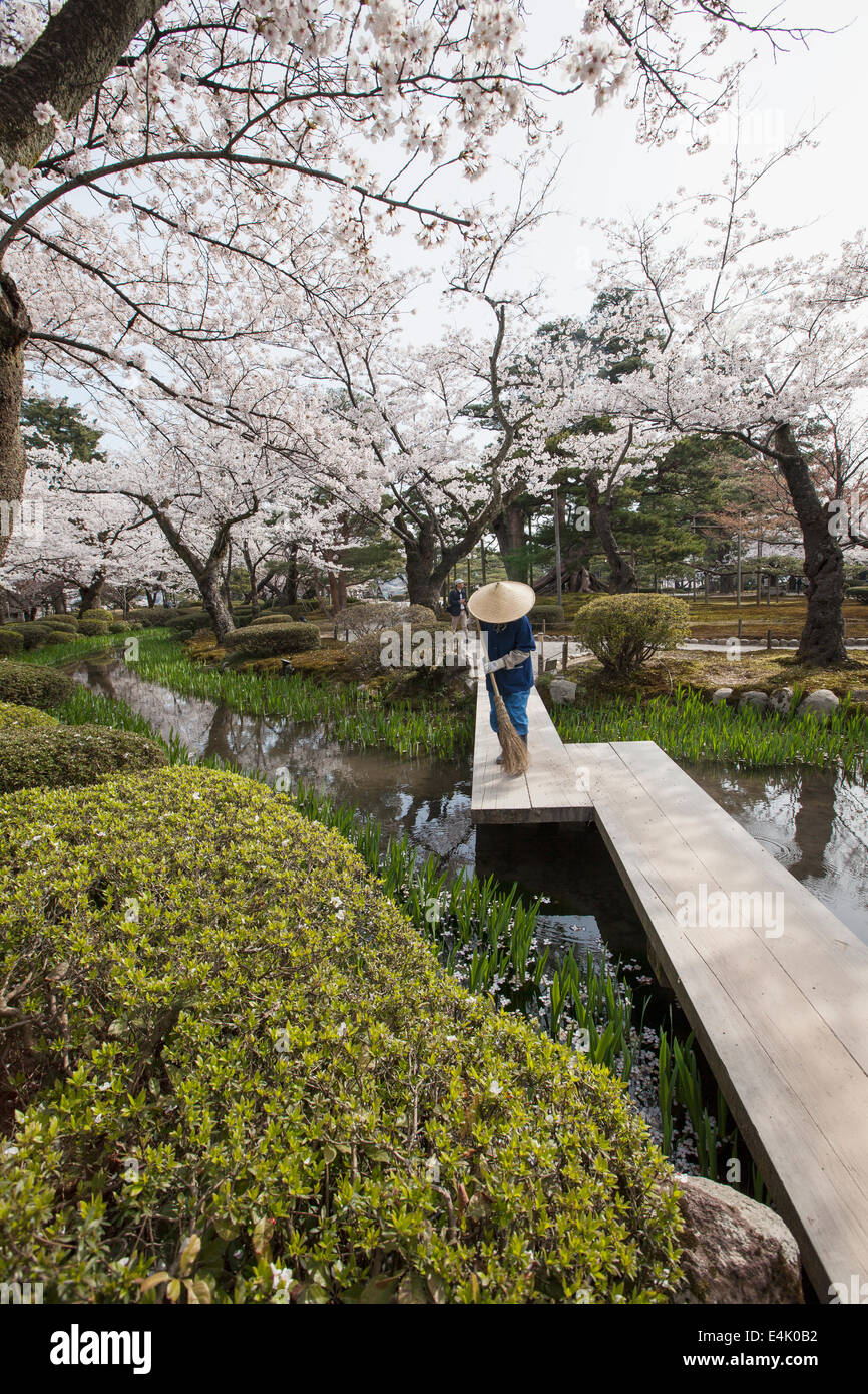 Weibliche Platzwart Holzsteg im Kenrokuen Garten fegen. Stockfoto