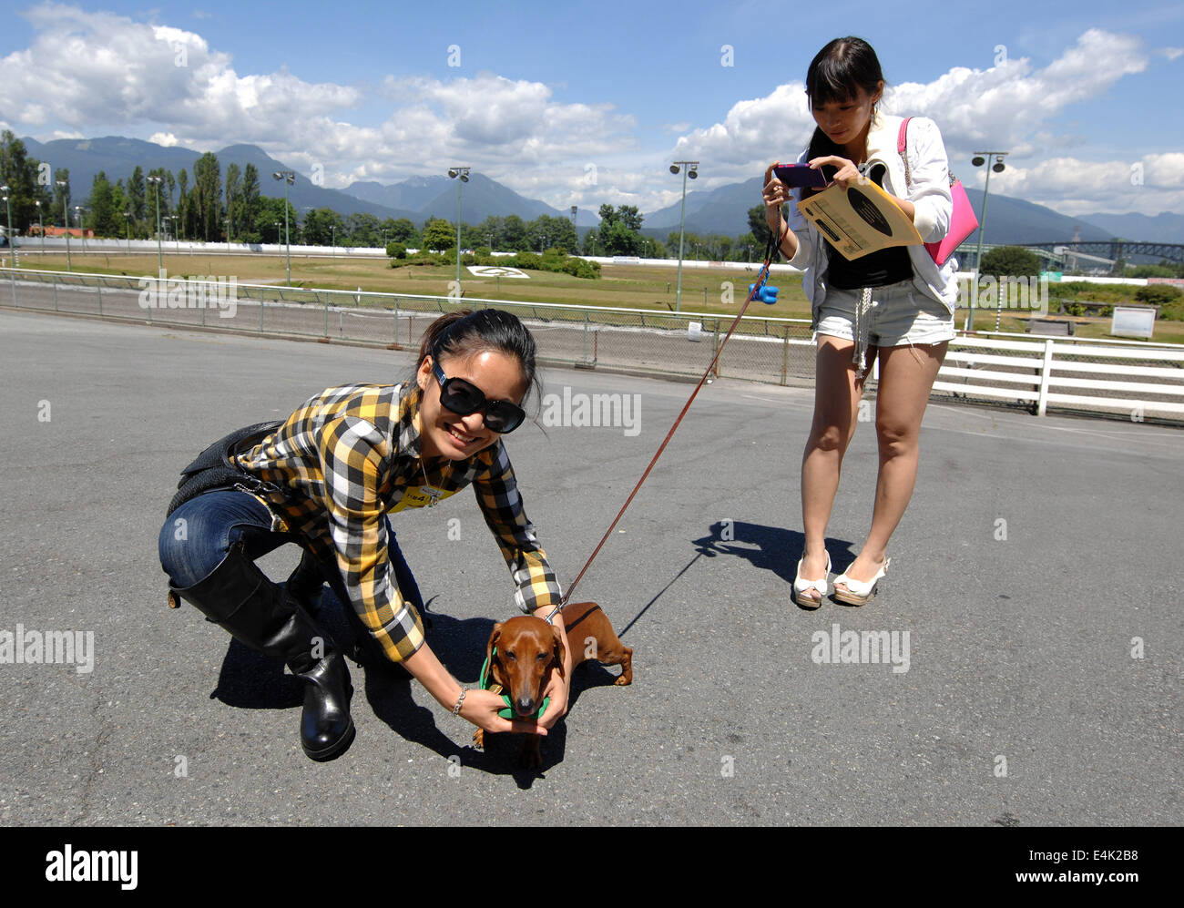 Vancouver, Kanada. 13. Juli 2014. Emma (L) posiert mit Frankie vor Beginn der jährlichen Wiener Dog Racing bei Hastings Race Course in Vancouver, Kanada, 13. Juli 2014. Mehr als 70 Dackel liefen bis zur Ziellinie. © Sergei Bachlakov/Xinhua/Alamy Live-Nachrichten Stockfoto