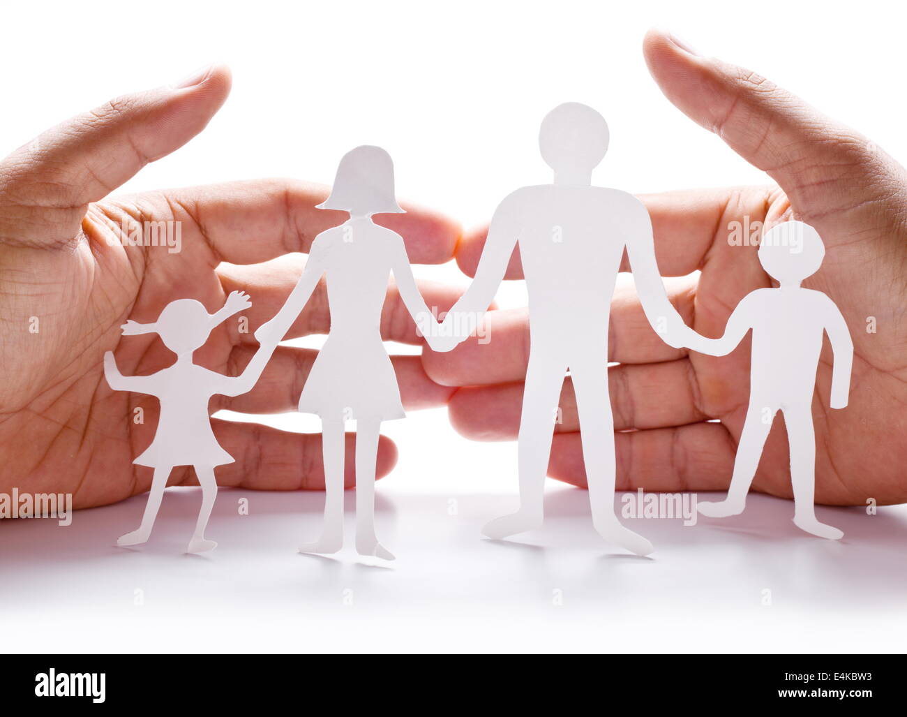 Pappfiguren der Familie auf einem weißen Hintergrund. Das Symbol der Einheit und des Glücks. Händen umarmen sanft die Familie. Stockfoto