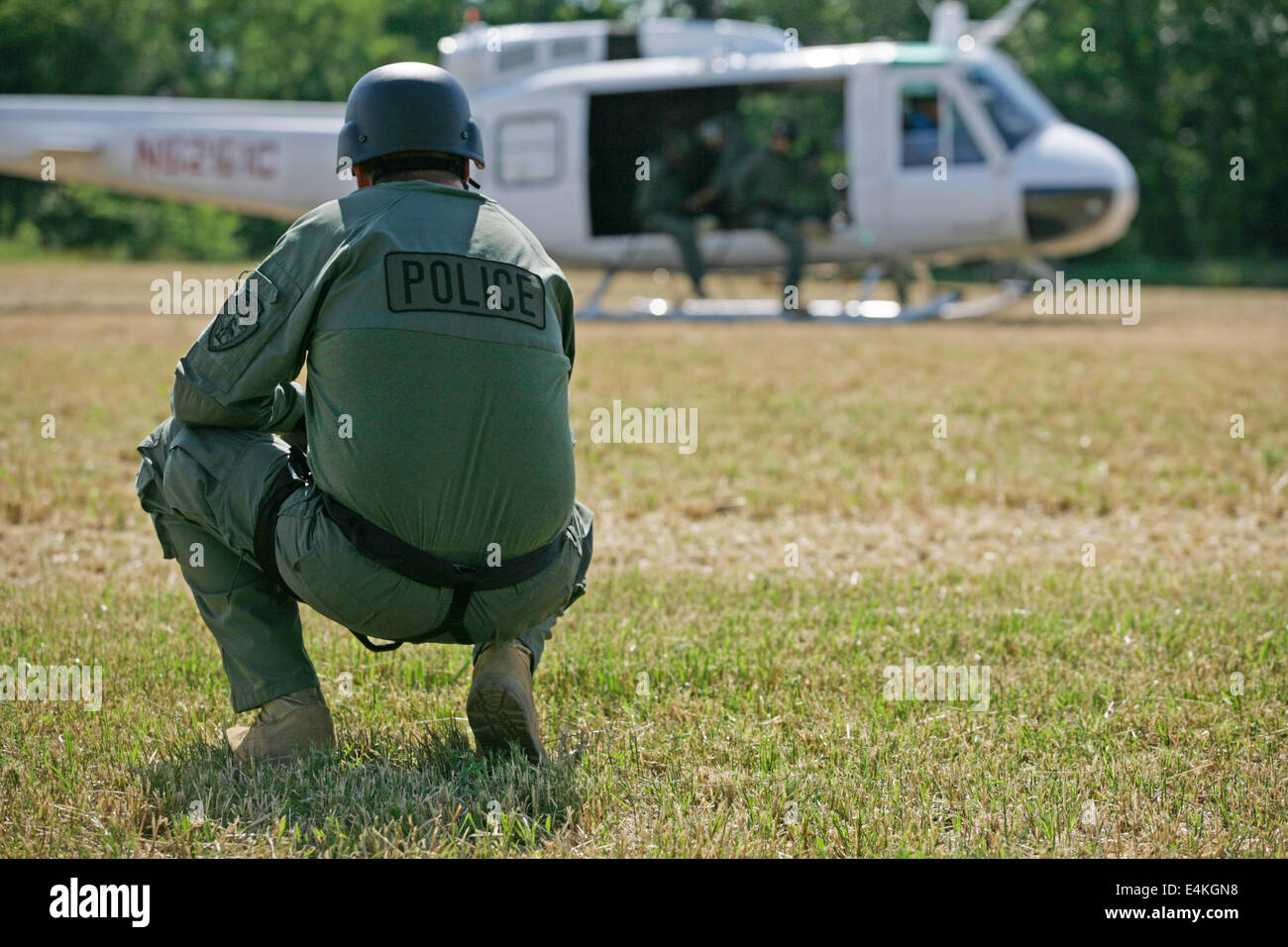 Polizist kniet im Feld mit dem Hubschrauber Stockfoto