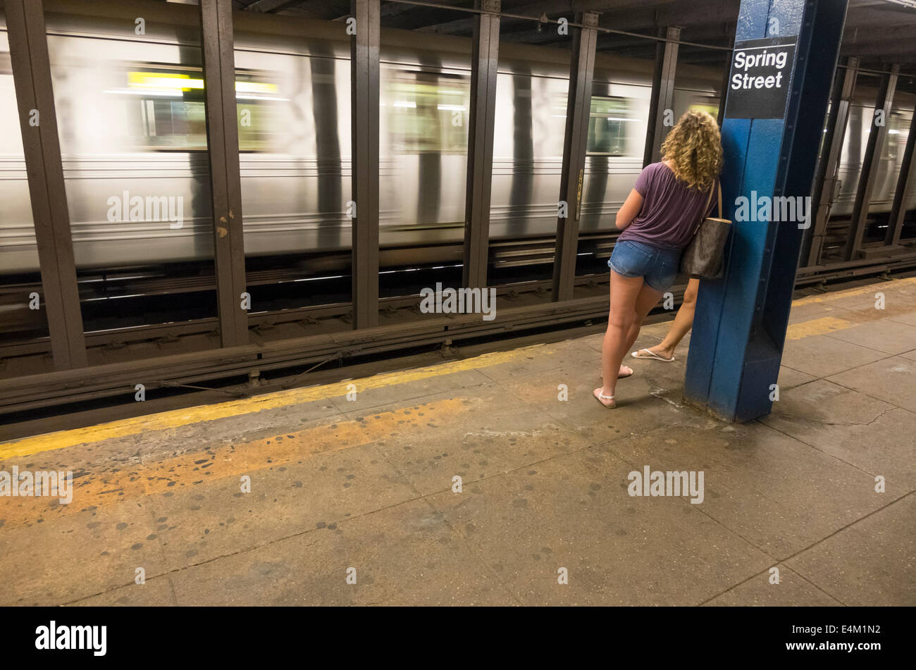 Zwei junge Frauen in kurzen Hosen warten auf eine u-Bahn Haltestelle Spring Street in Lower Manhattan Stockfoto