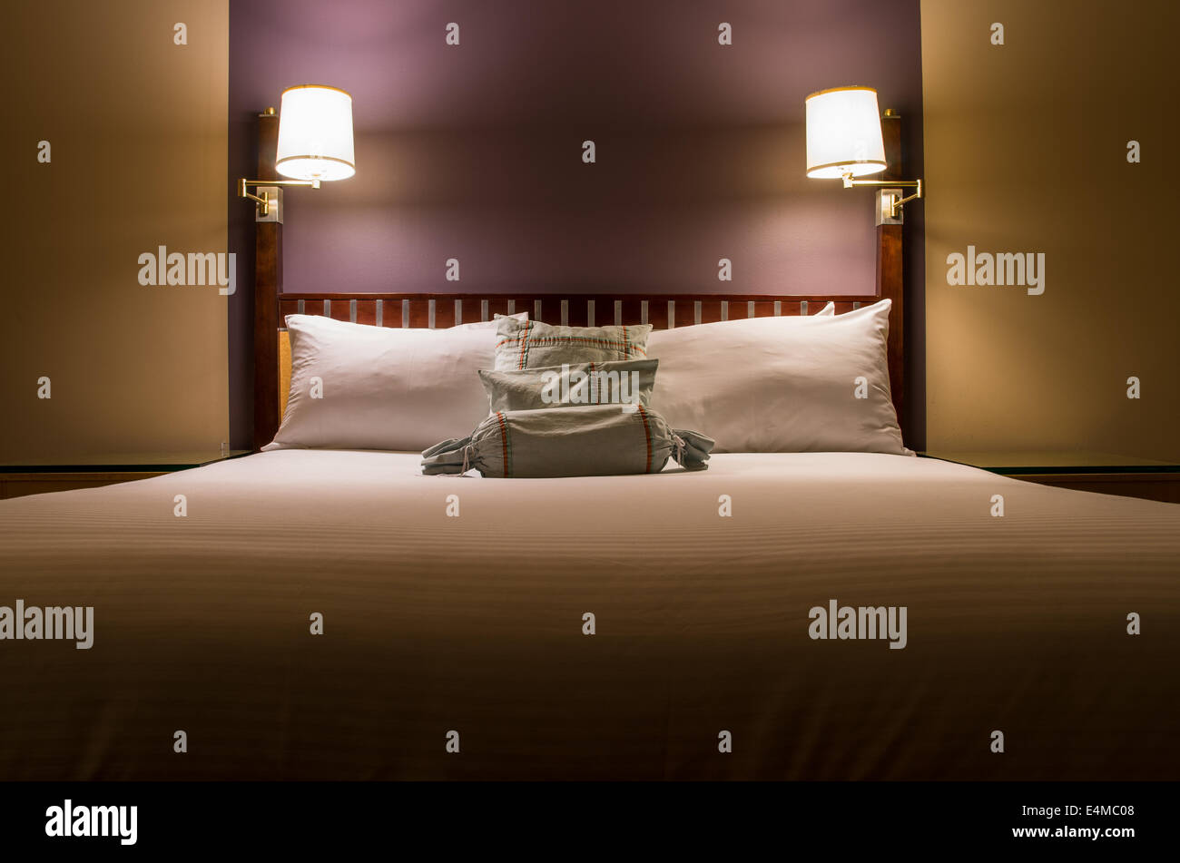 Bett mit Kissen und Wandlampen Stockfoto