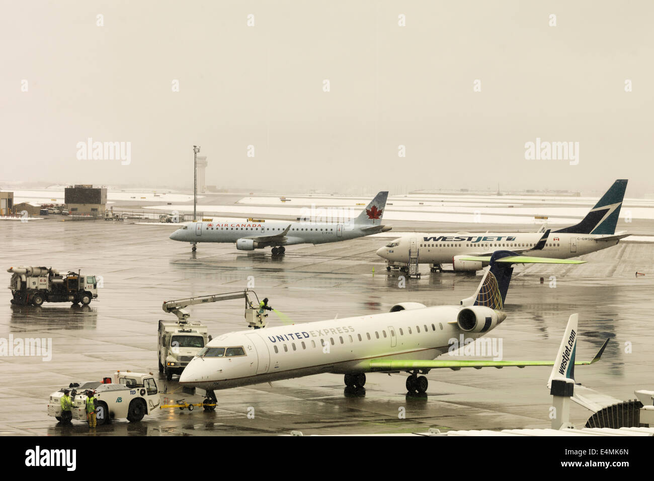 Vor dem Start vom Flughafen Calgary während eines Schneesturms Flugzeuge Auftausalz. Stockfoto