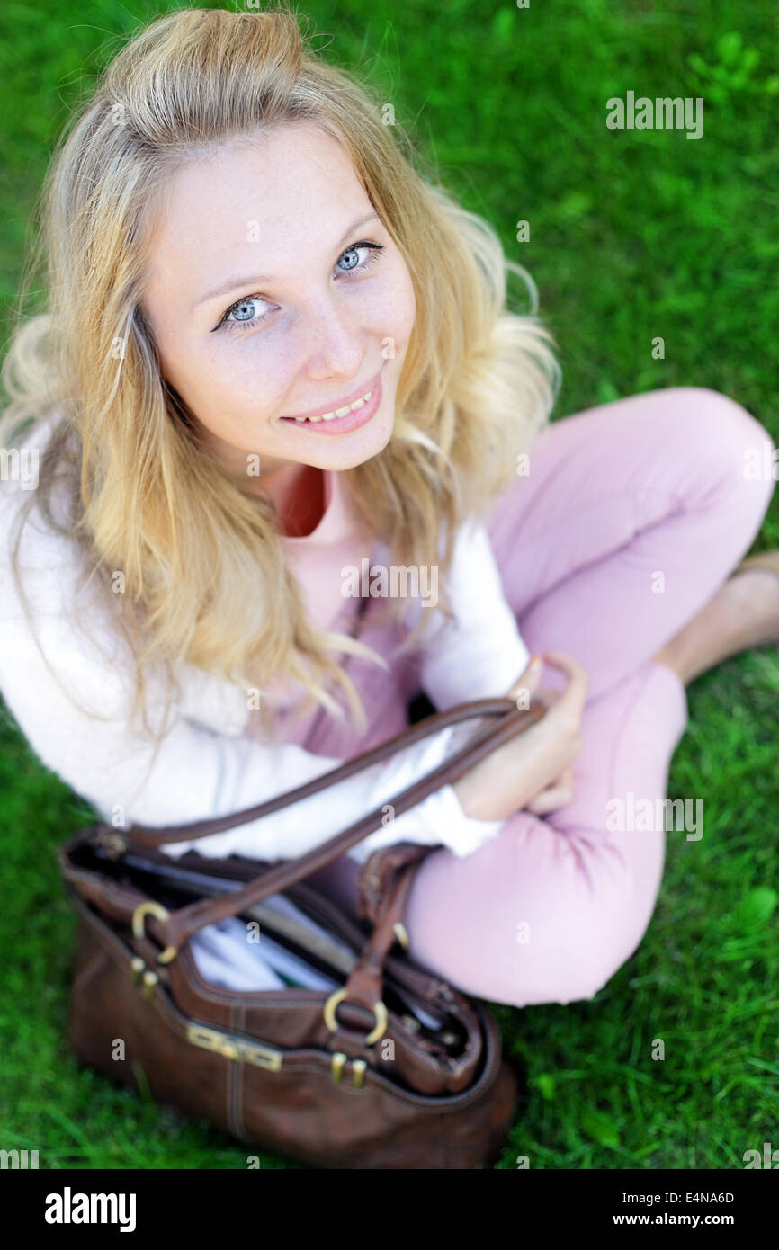 unbeschwerte Frau sitzt in einem grünen Feld Stockfoto
