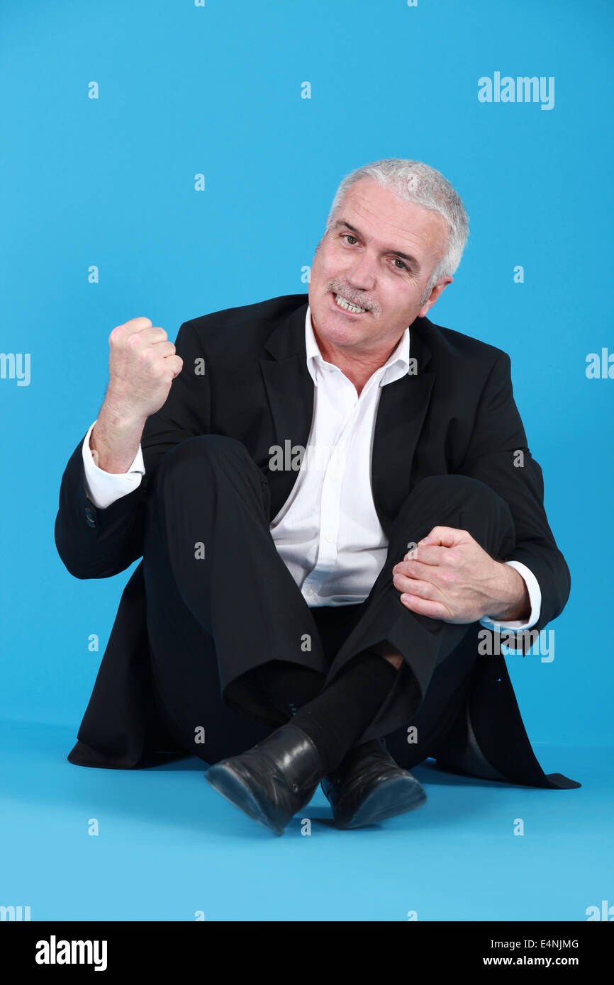 Ein verärgerter Mann sitzt im Schneidersitz Stockfoto