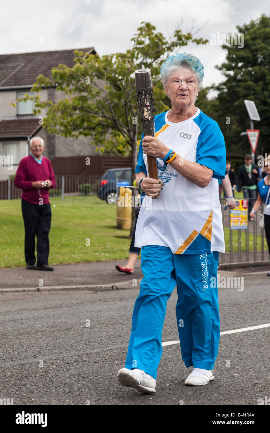 Ayrshire, Schottland, Vereinigtes Königreich. 15. Juli 2014. Frau Myra Sim mit der Leitung durch die Stadt Dalry in North Ayrshire, Schottland, während der Königin Baton Relay für den Glasgow2014 Commonwealth Games. Stockfoto