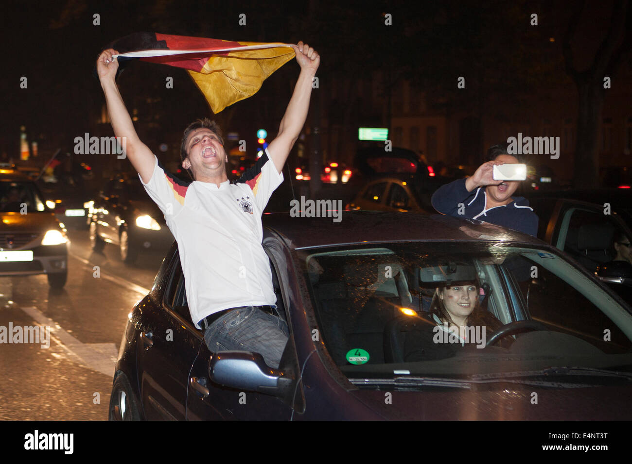 Wiesbaden, Deutschland. 14. Juli 2014. Deutschland gewinnt das FIFA WM 2014. Menschen in ihren Autos und auf der Straße, jubeln und feiern in der Innenstadt von Wiesbaden nach Deutschlands Sieg über Argentinien im Endspiel. Ein Mann mit einer deutschen Flagge hoch. Bewegungsunschärfe. Bildnachweis: Oliver Kessler/Alamy Live-Nachrichten Stockfoto