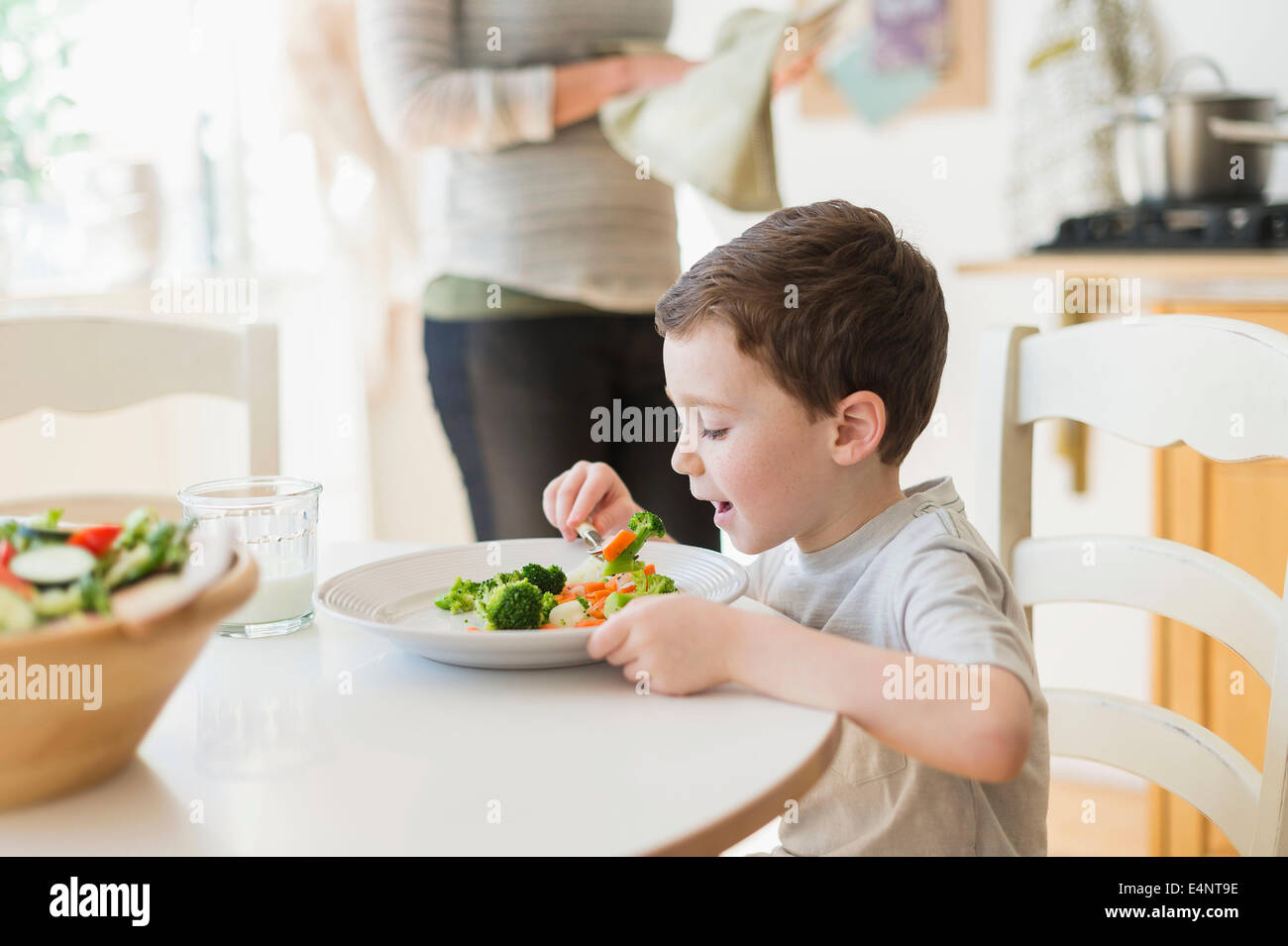 Junge (6-7), gesund essen, Mutter im Hintergrund Stockfoto