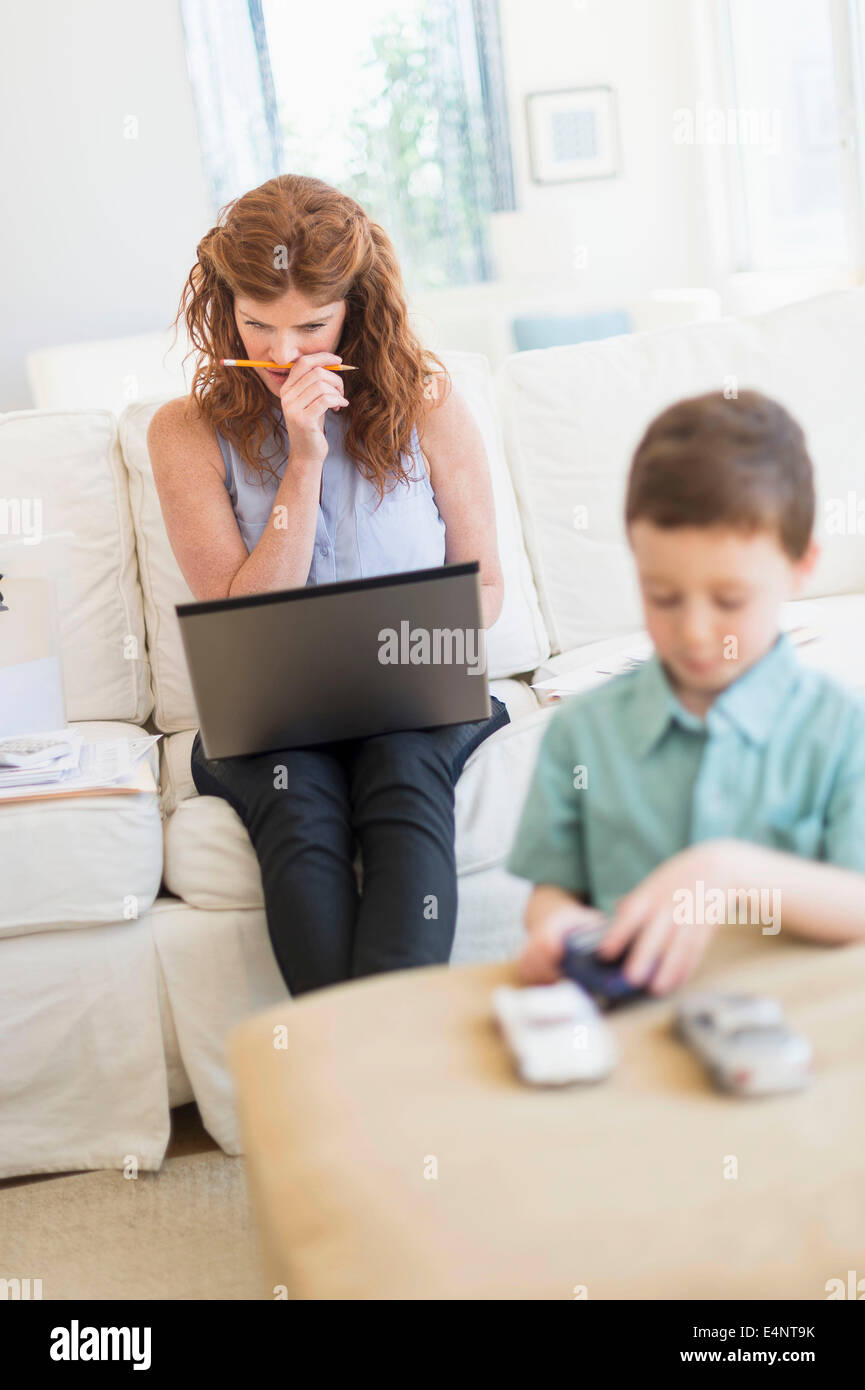 Mutter mit Laptop, Sohn (6-7) spielen mit Spielzeug-Autos Stockfoto
